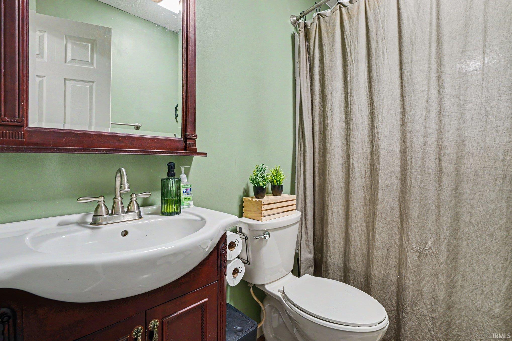 Bathroom featuring a white porcelain sink, dark wood-finish vanity, brushed nickel faucet, and a wall-mounted mirror with an integrated shelf
