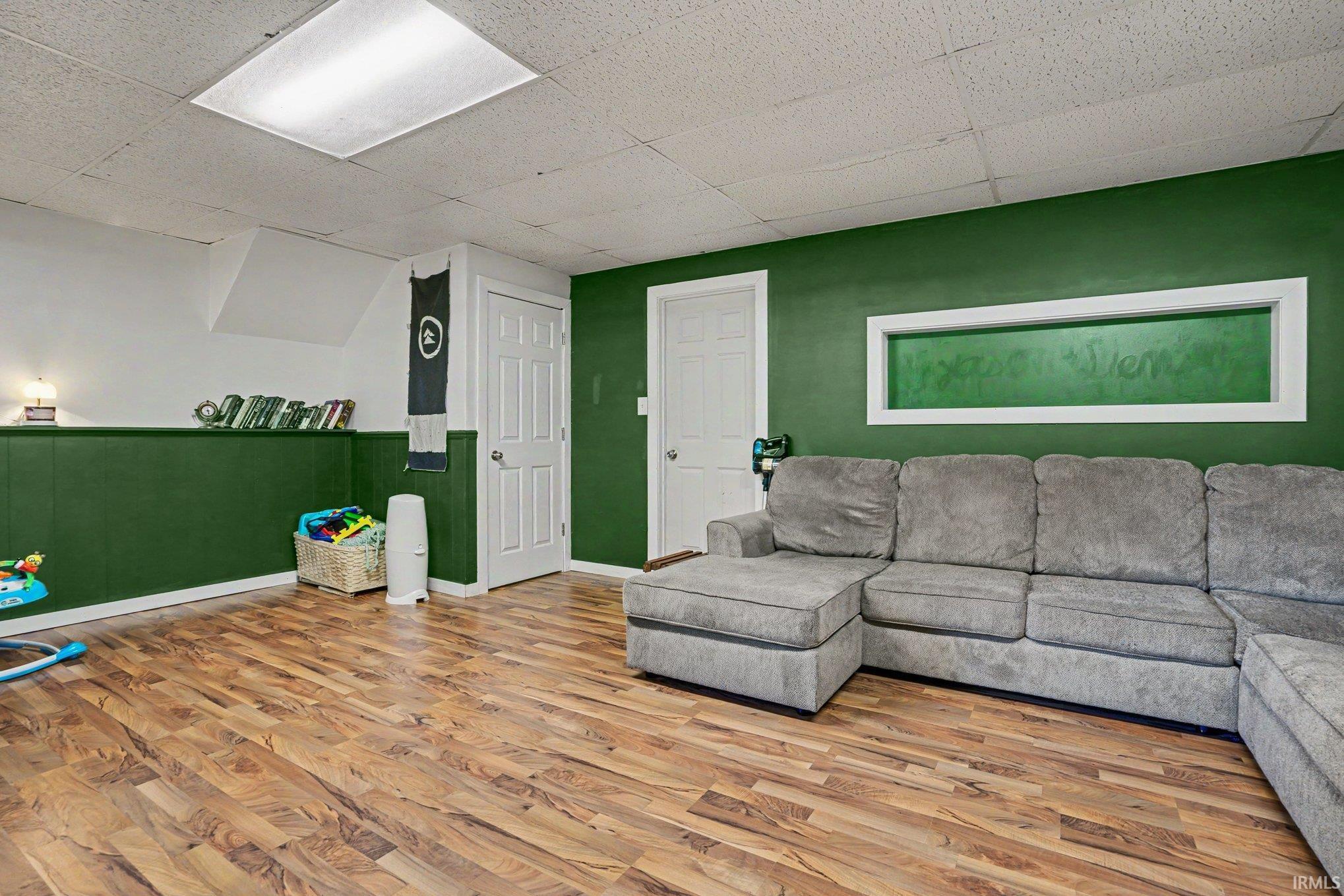 Spacious interior with wood-finish flooring, two-tone wall paint, white trim, and a drop ceiling with recessed lighting
