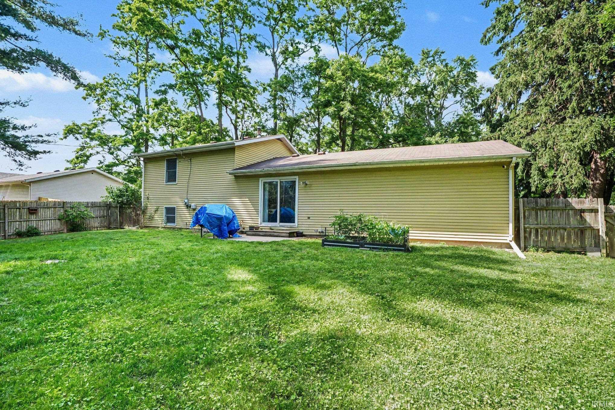 Expansive grassy yard with mature trees and a fenced perimeter