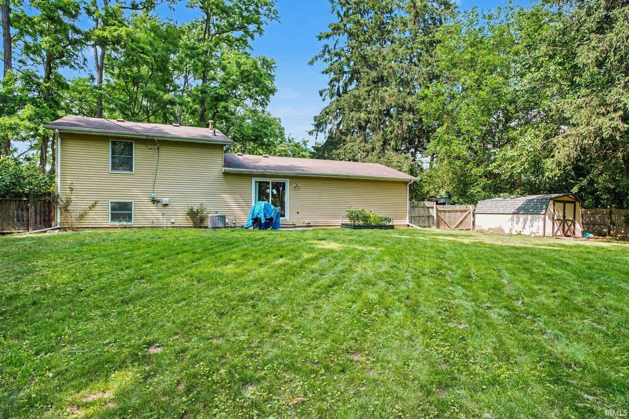 Spacious backyard featuring a large green lawn, a utility shed, and a privacy fence