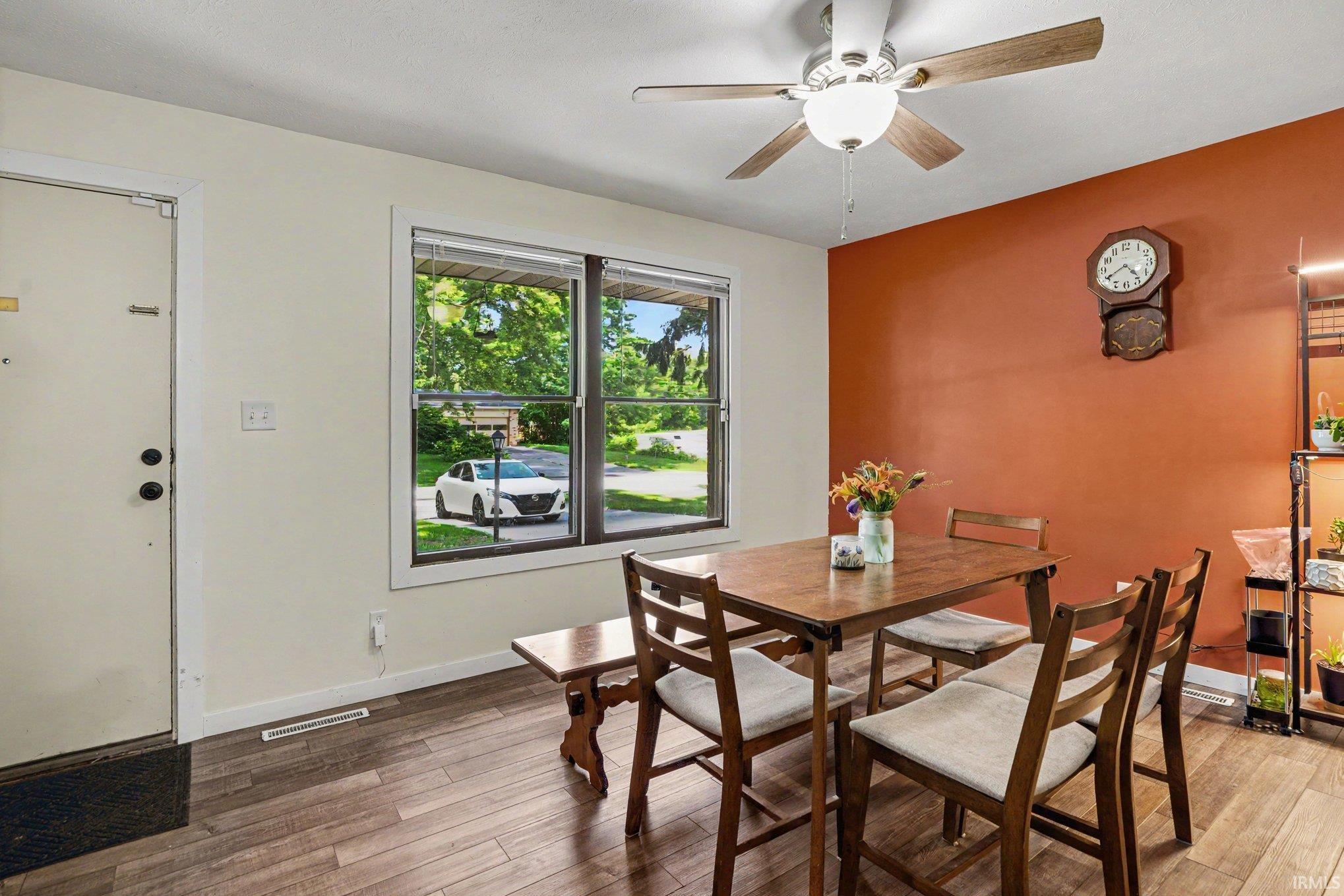 Interior space featuring wood-finish flooring, a ceiling fan with light fixture, and a window with blinds