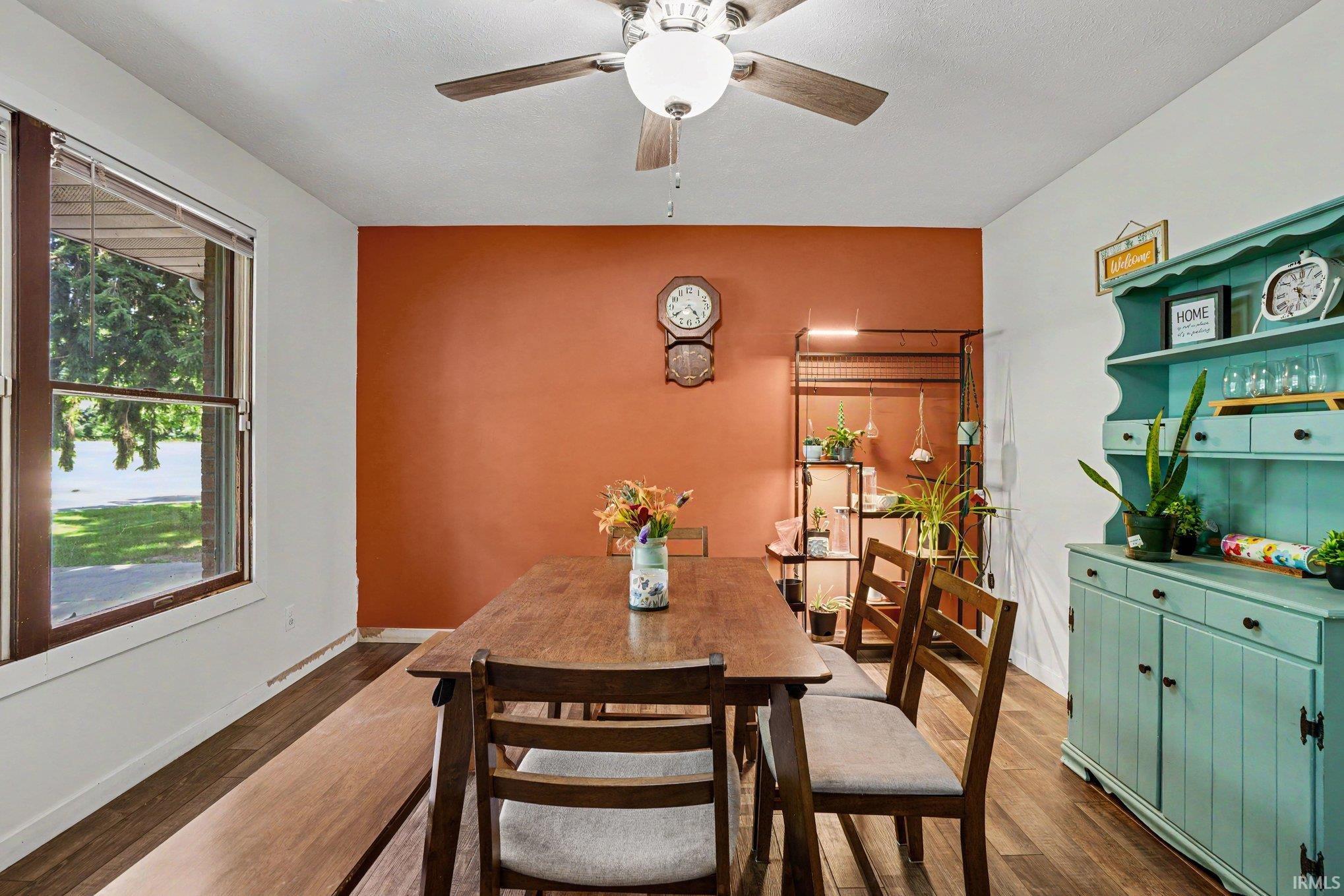 Dining area featuring wood-finish flooring, a ceiling fan with integrated lighting, and a large window
