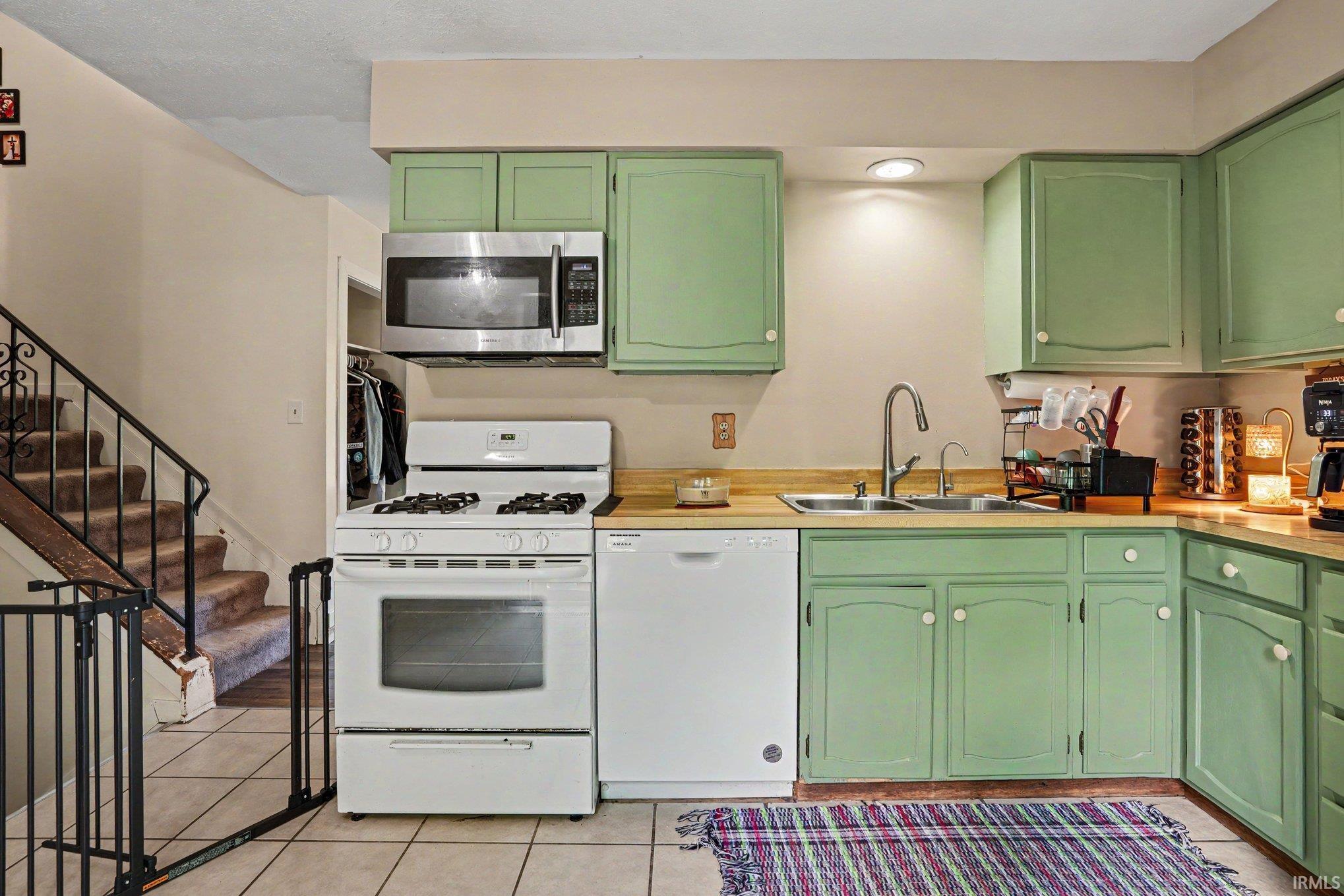 Kitchen featuring wood-finish countertops, light green cabinetry, and tile flooring
