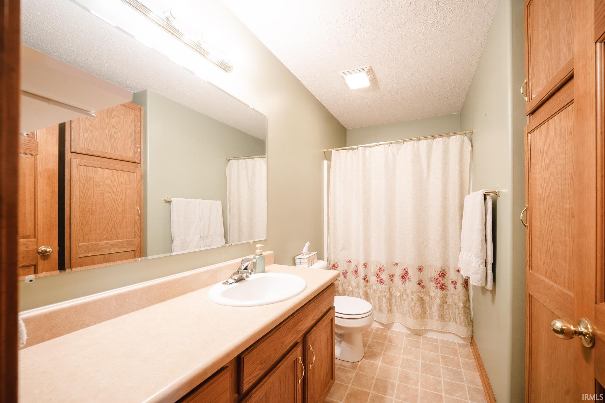 Bathroom featuring a vanity with an integrated sink, wood-finish cabinetry, and a full-width mirror