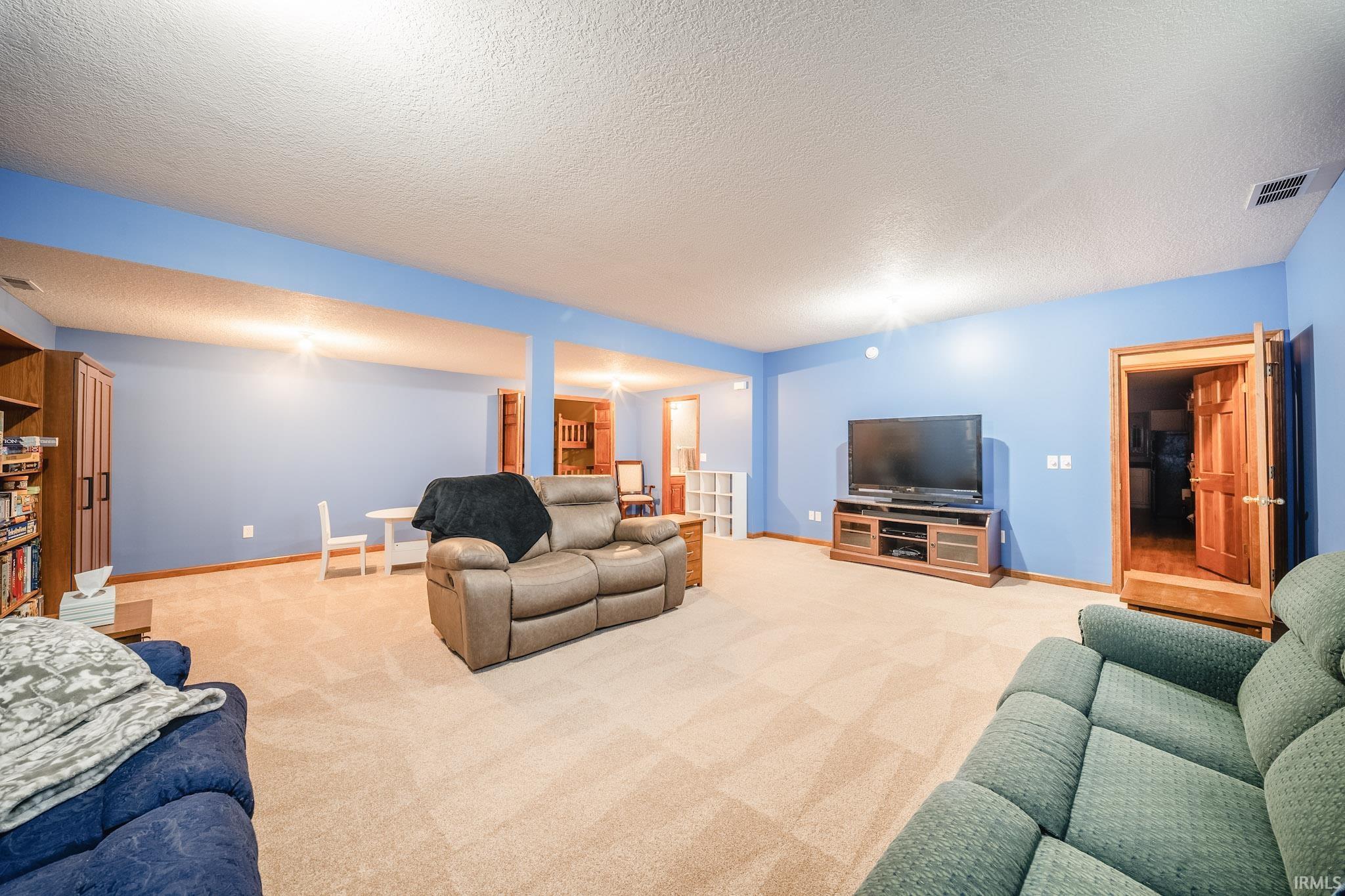 Spacious recreational room featuring light blue walls, recessed lighting, and carpet flooring
