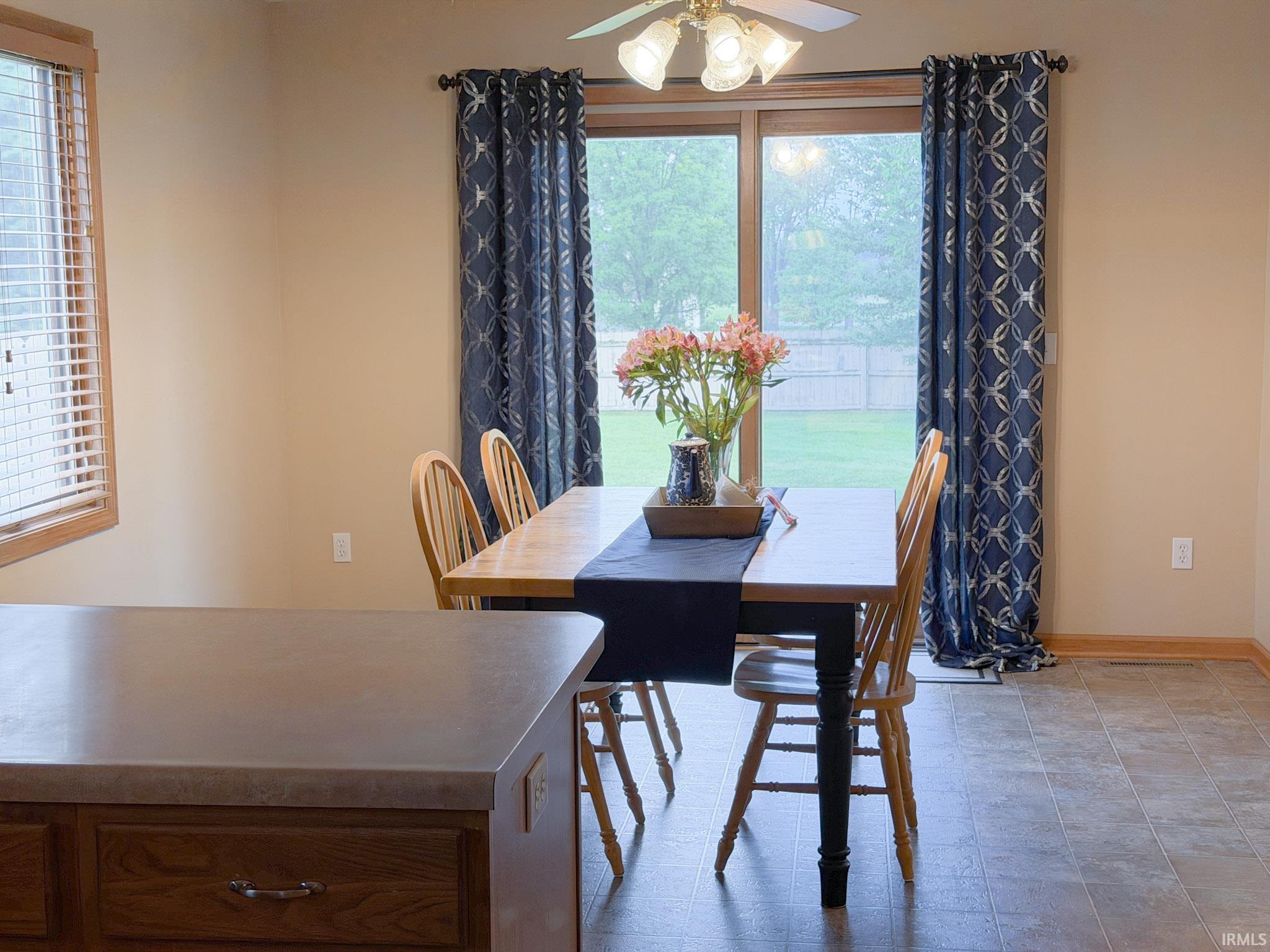 Dining area featuring a ceiling fan with integrated lighting, sliding glass door, and tile-look flooring