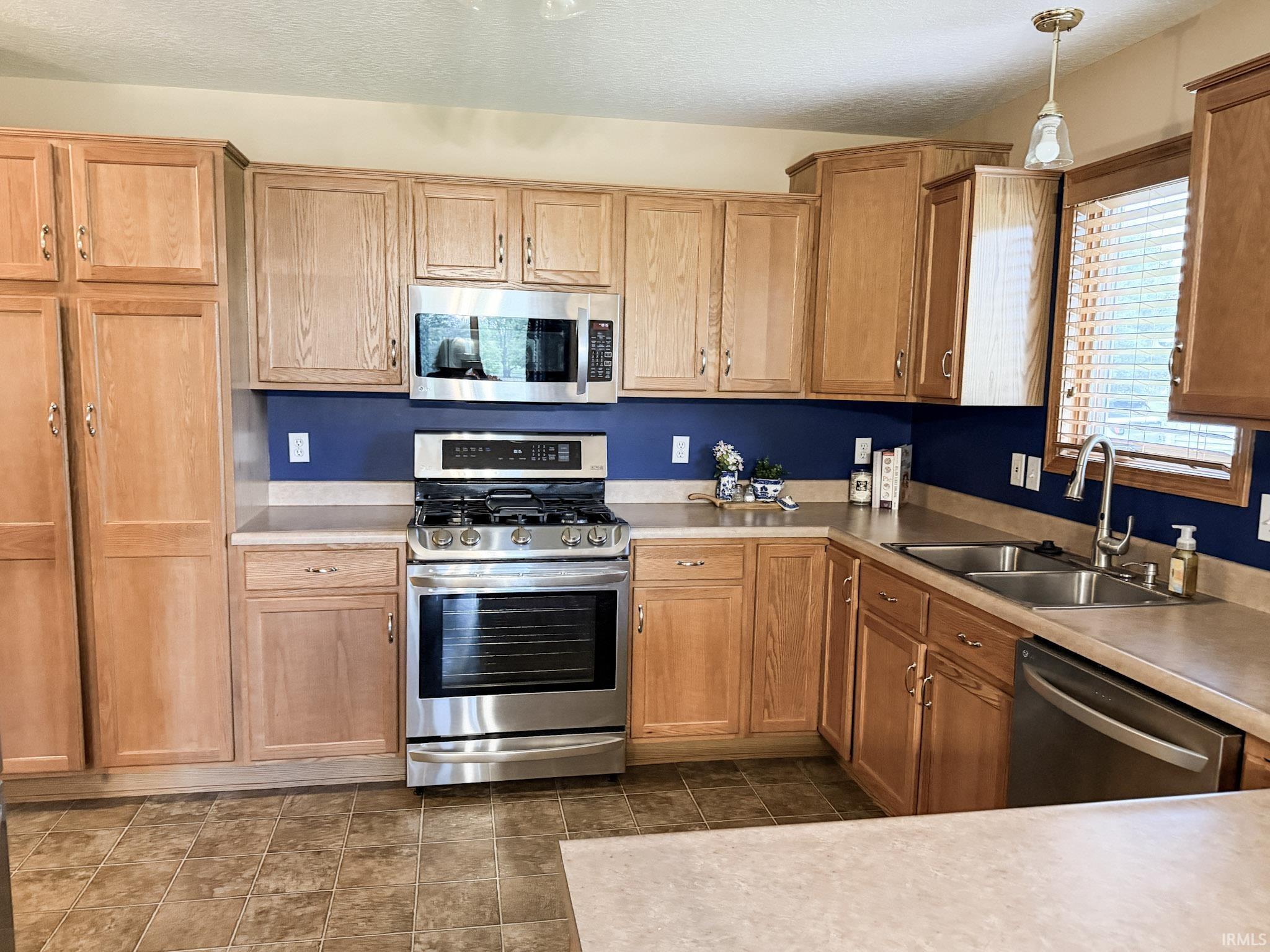Kitchen featuring wood cabinetry, stainless steel appliances, dual basin sink, and laminate countertops