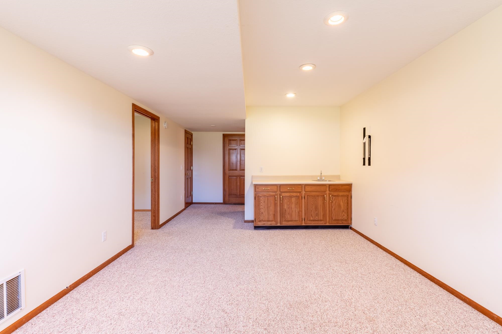 Recessed lighting illuminates an open space with light-colored carpeting