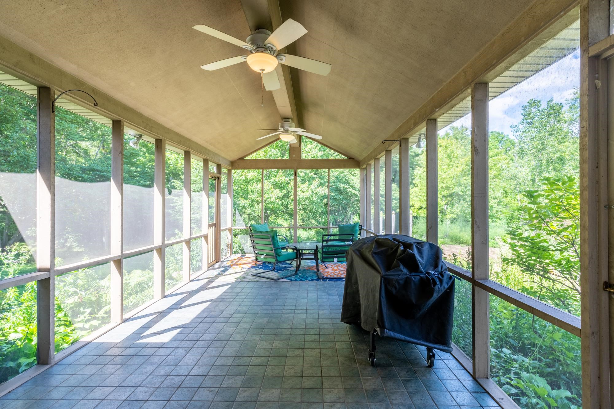 Expansive screened porch featuring a vaulted ceiling and two ceiling fans