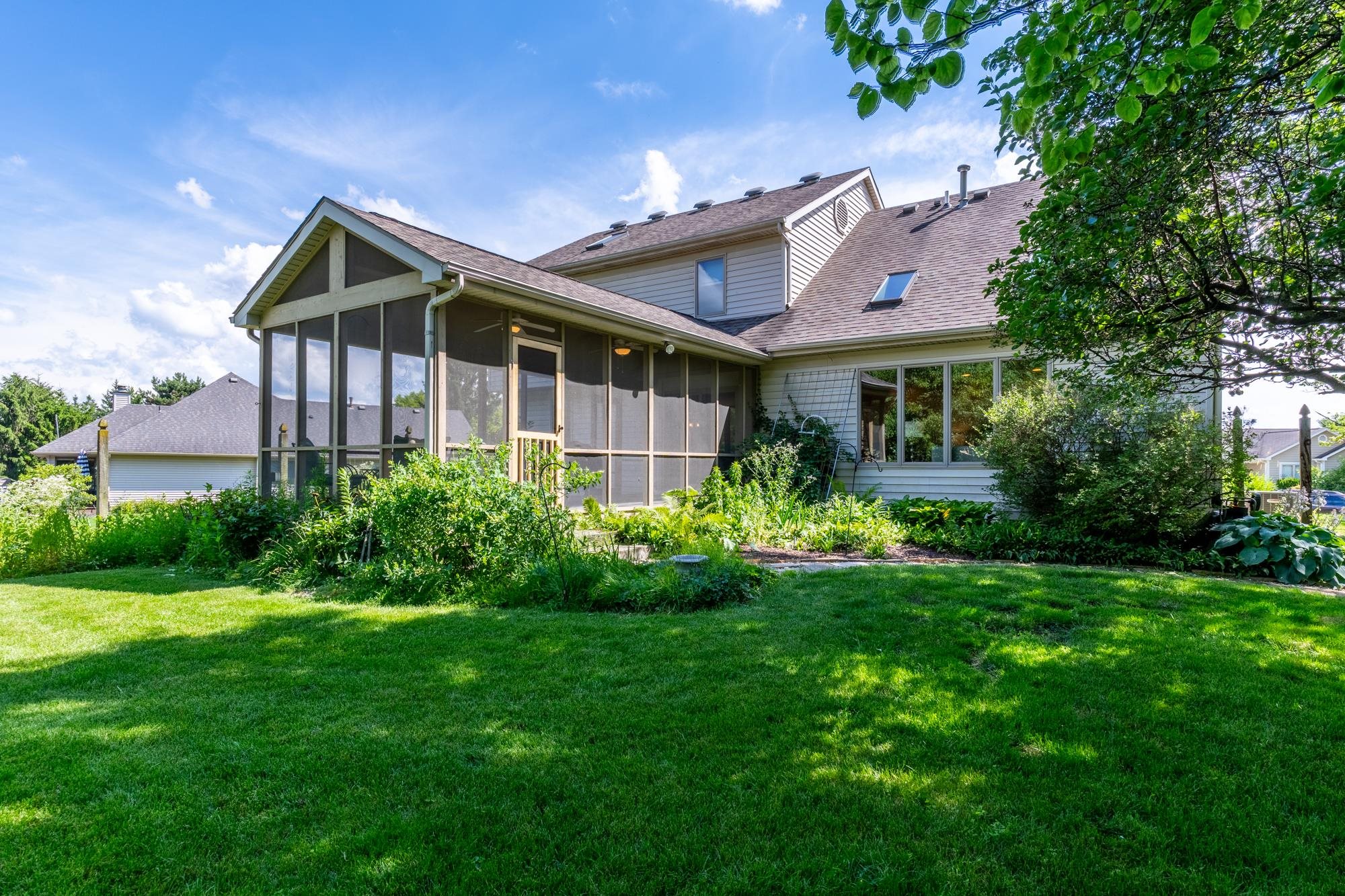 Expansive backyard featuring a screened porch, dormer window, skylight, and large picture windows