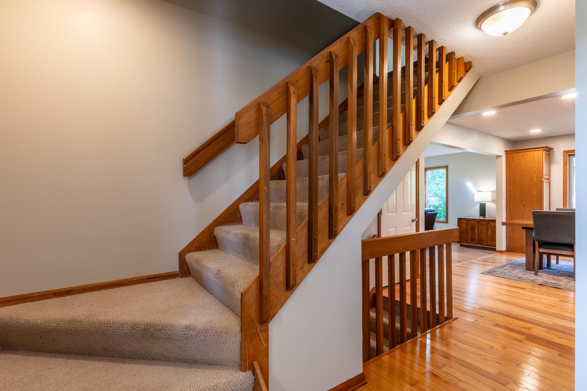 Carpeted staircase with natural wood balusters and handrail