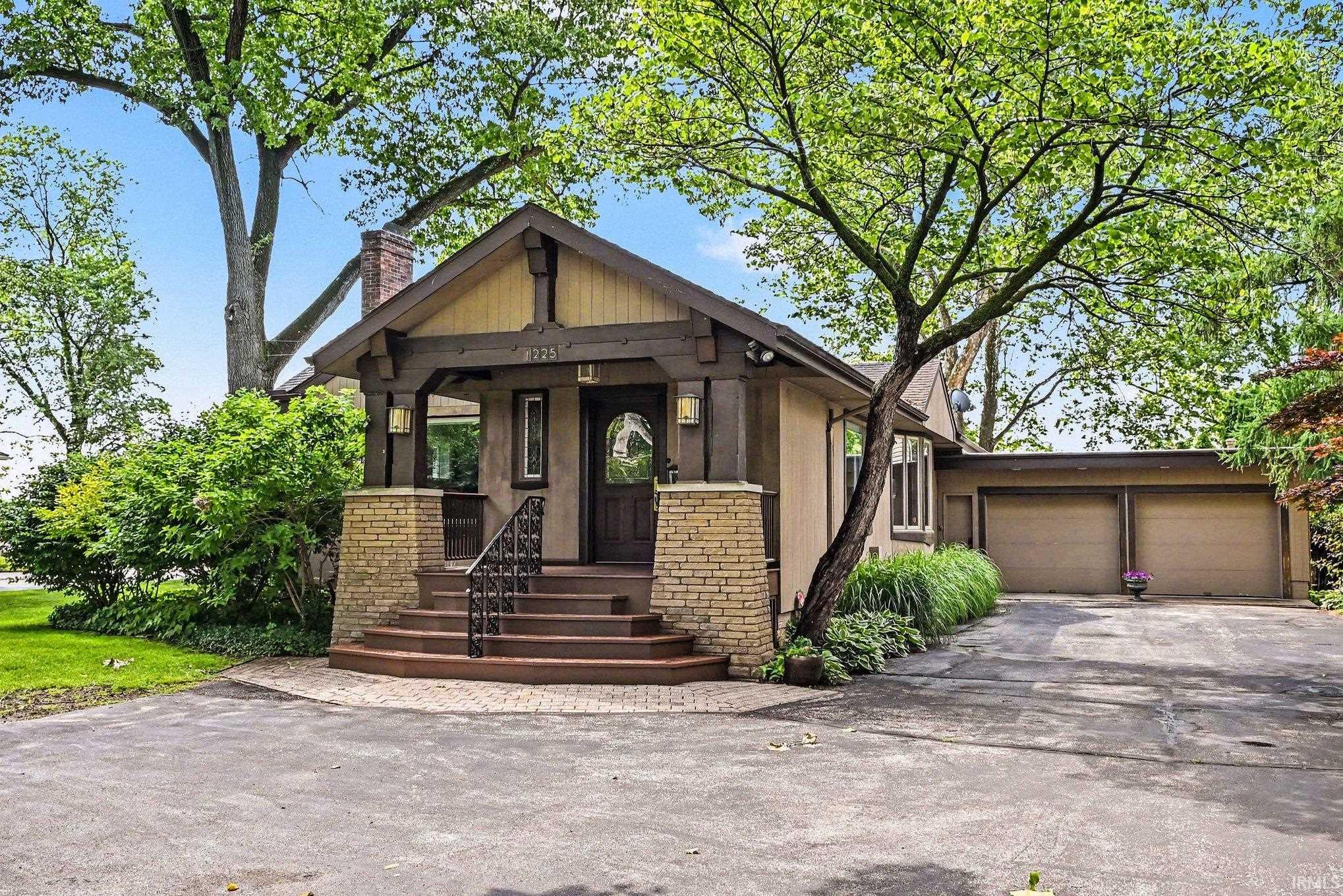Craftsman-style home featuring a covered front porch with stone columns and dark wood accents