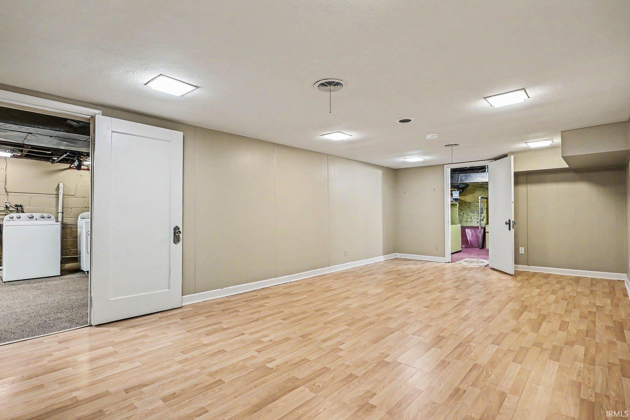 Spacious room featuring wood-finish flooring, neutral-toned walls, and recessed ceiling lighting
