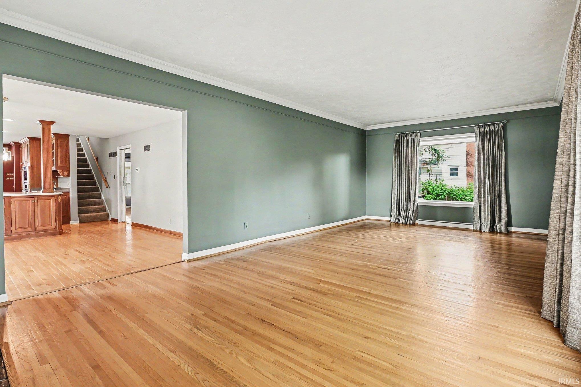 Spacious interior room featuring wood-finish flooring and a wide window opening