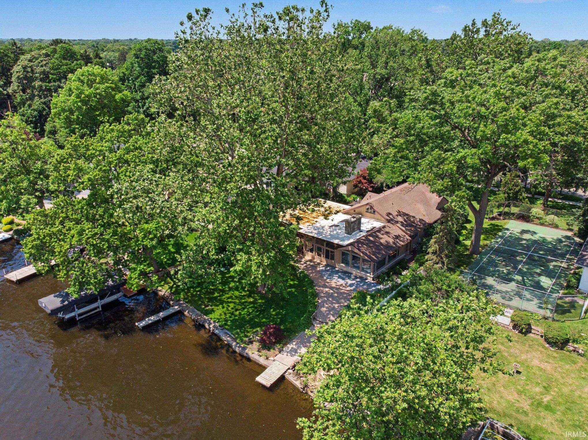Waterfront property featuring extensive mature tree coverage, gardens, pier, dock and patio