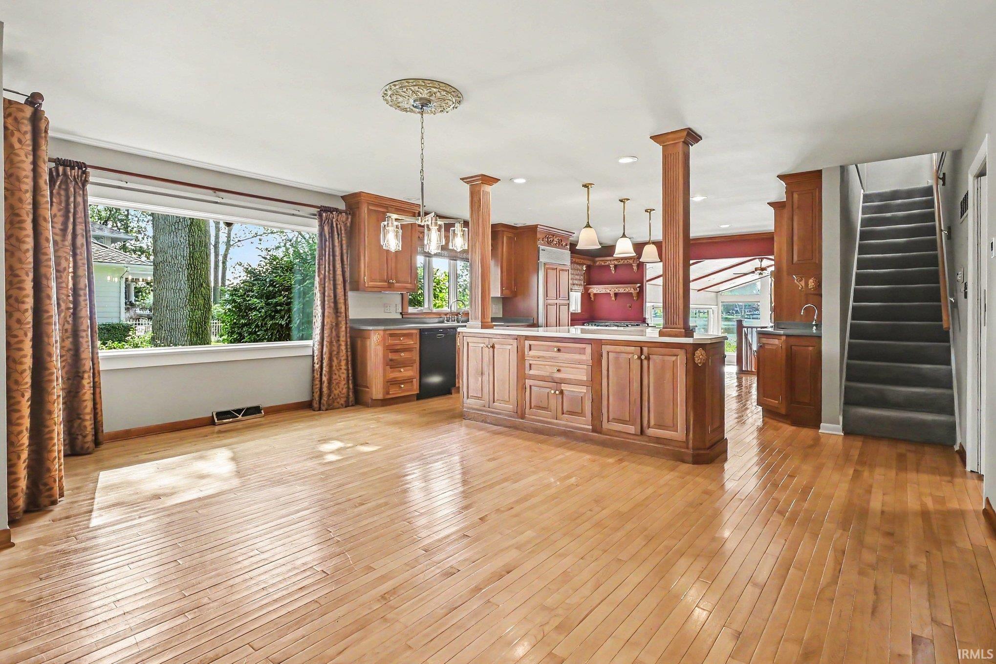Open-concept living space featuring wood-finish flooring, a large picture window, and a kitchen island with built-in cabinetry