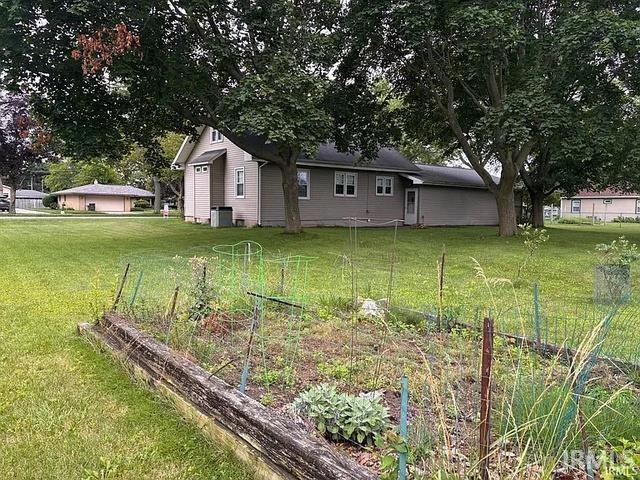 Expansive lawn featuring mature trees and a raised garden bed