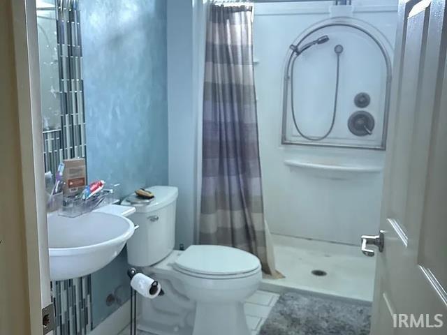 Pedestal sink with a wall-mounted mirror, stand-up shower, and tiled flooring