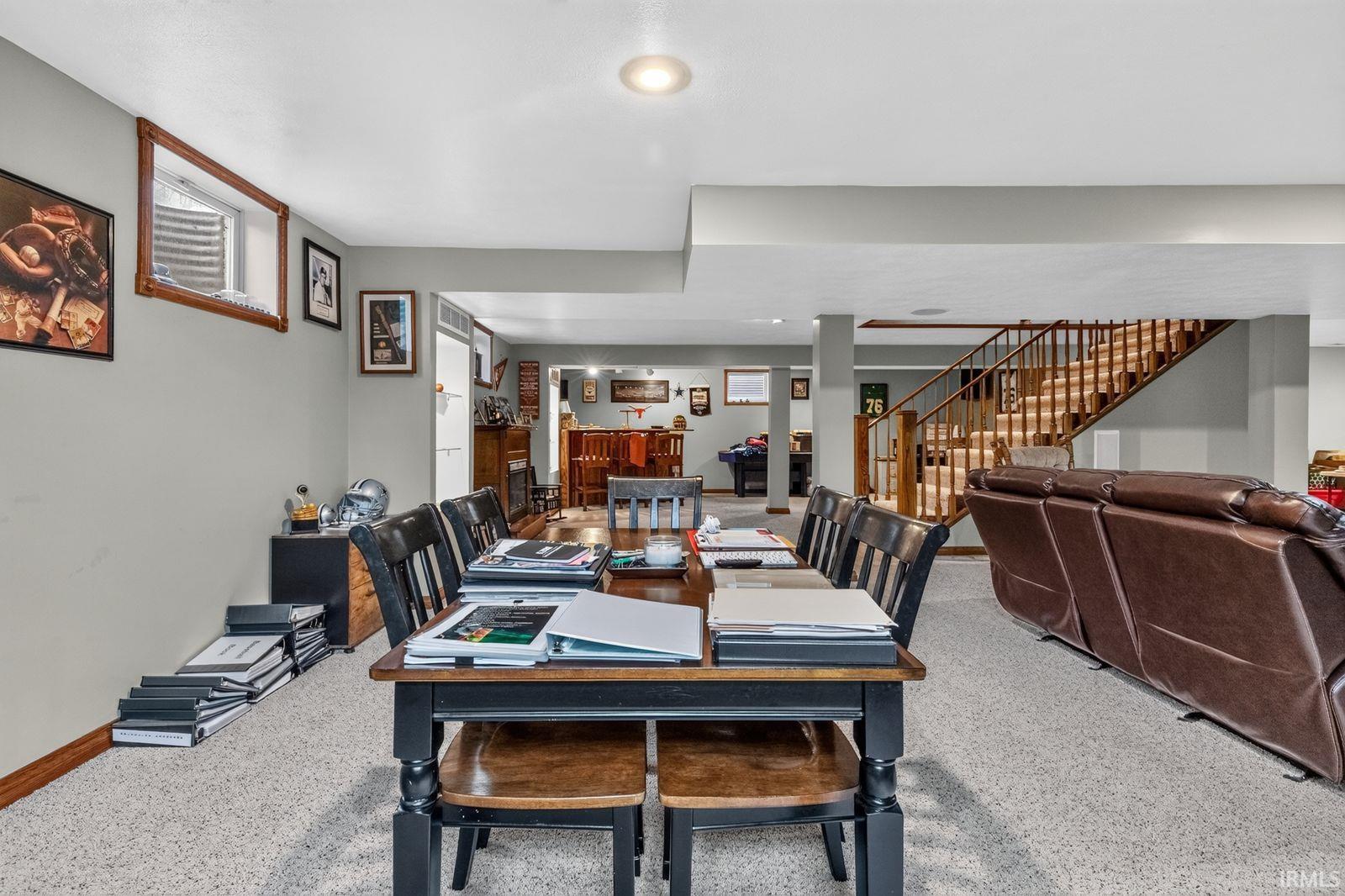 Spacious lower level featuring a full staircase with wood railings, recessed lighting, and a window well with wood trim