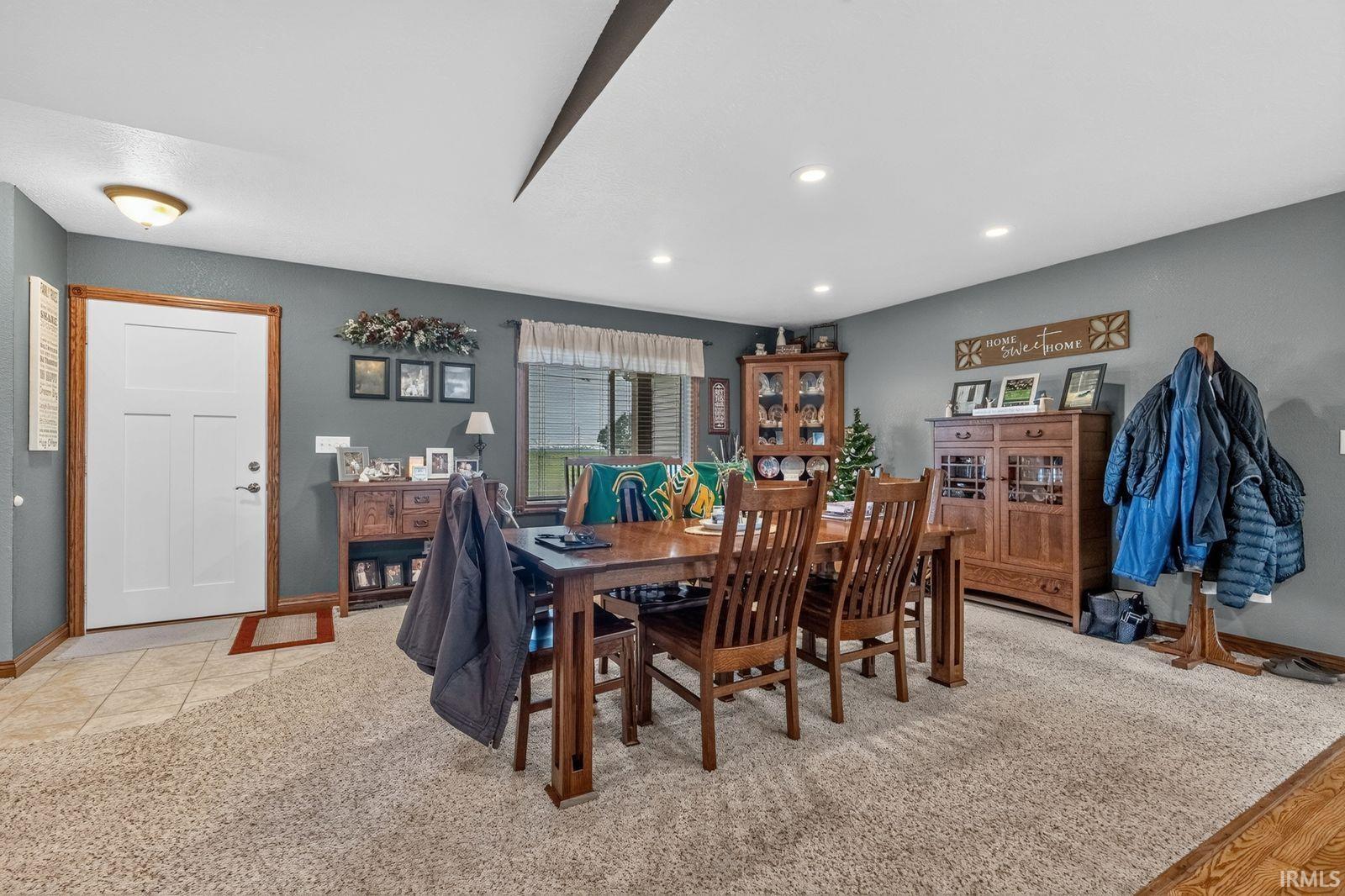 Spacious living area featuring neutral carpeting and a front entry door with a light wood-finish frame