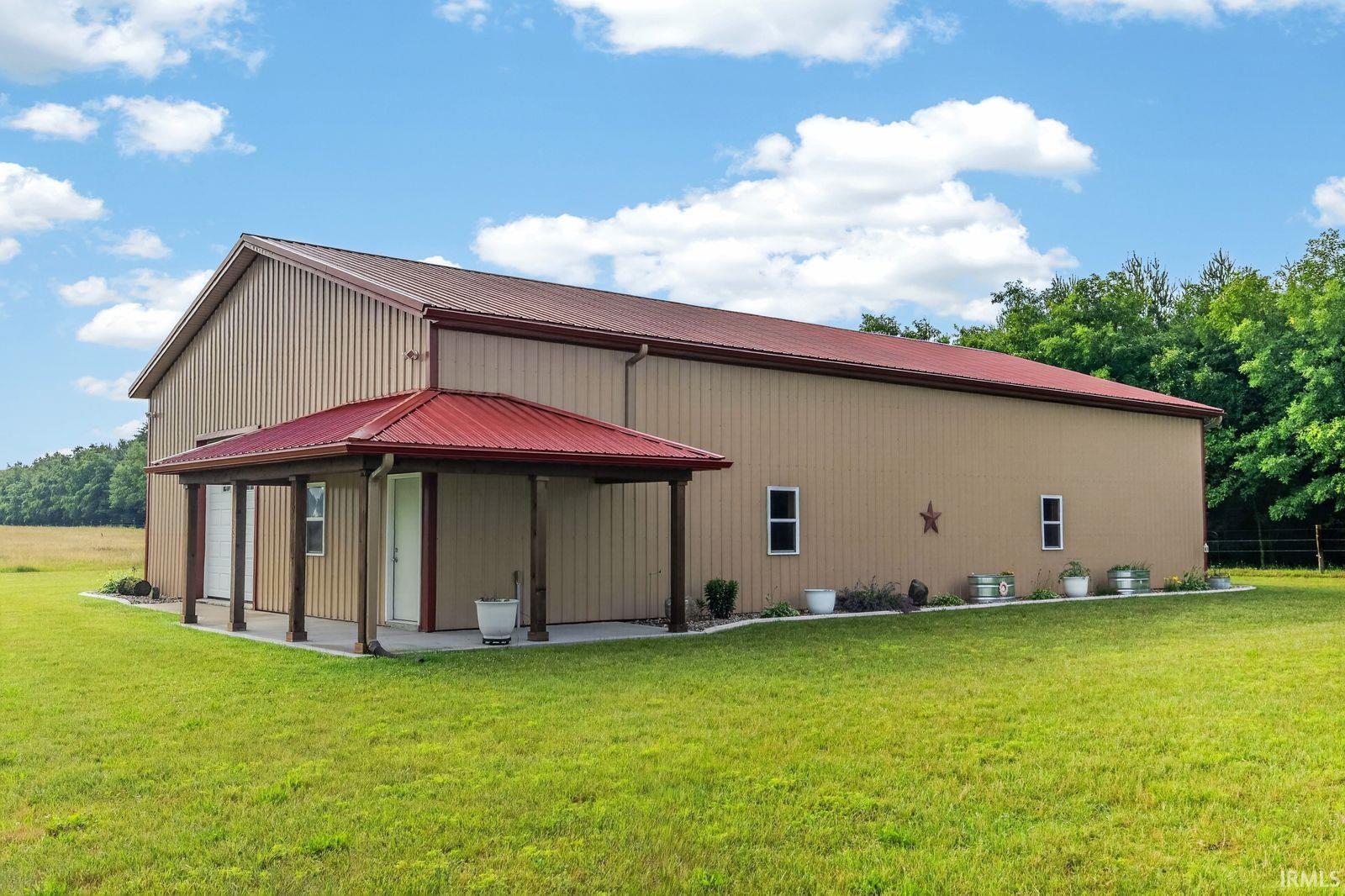 Metal building with a red metal roof and an extended covered porch