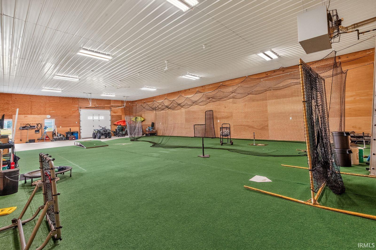 Spacious indoor athletic facility featuring green turf flooring and wood-paneled walls