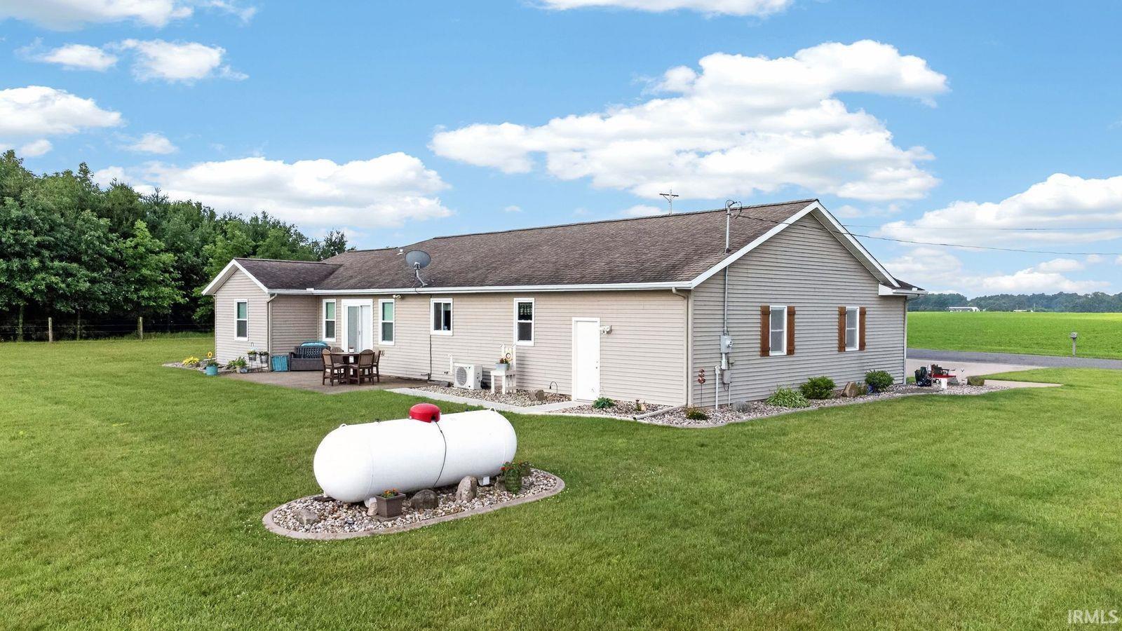 Ranch-style residence featuring neutral-toned siding, a dark shingle roof, and multiple exterior access points