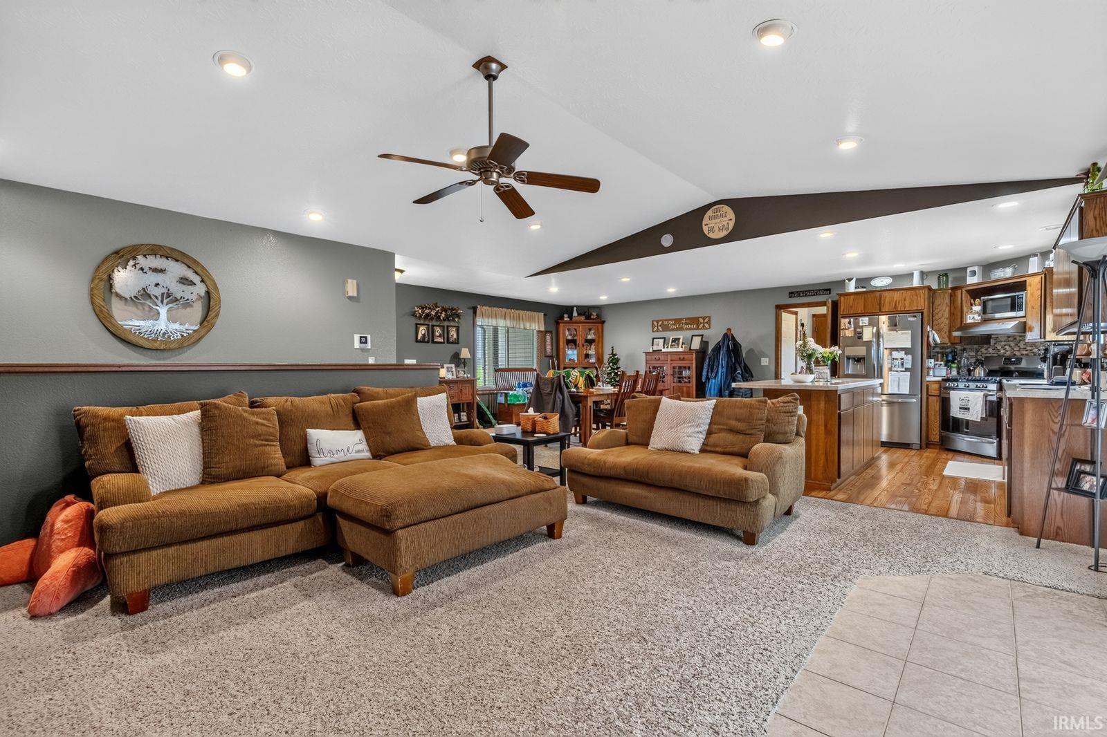Open-concept living space with vaulted ceilings, recessed lighting, and a ceiling fan