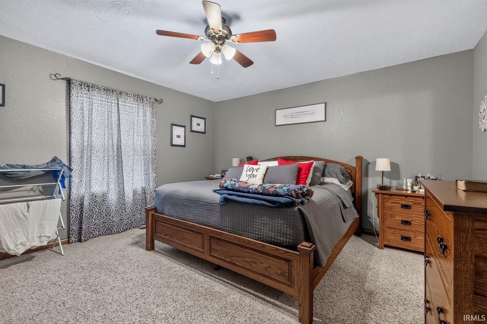 Carpeted room featuring a ceiling fan with light fixture and light-colored walls