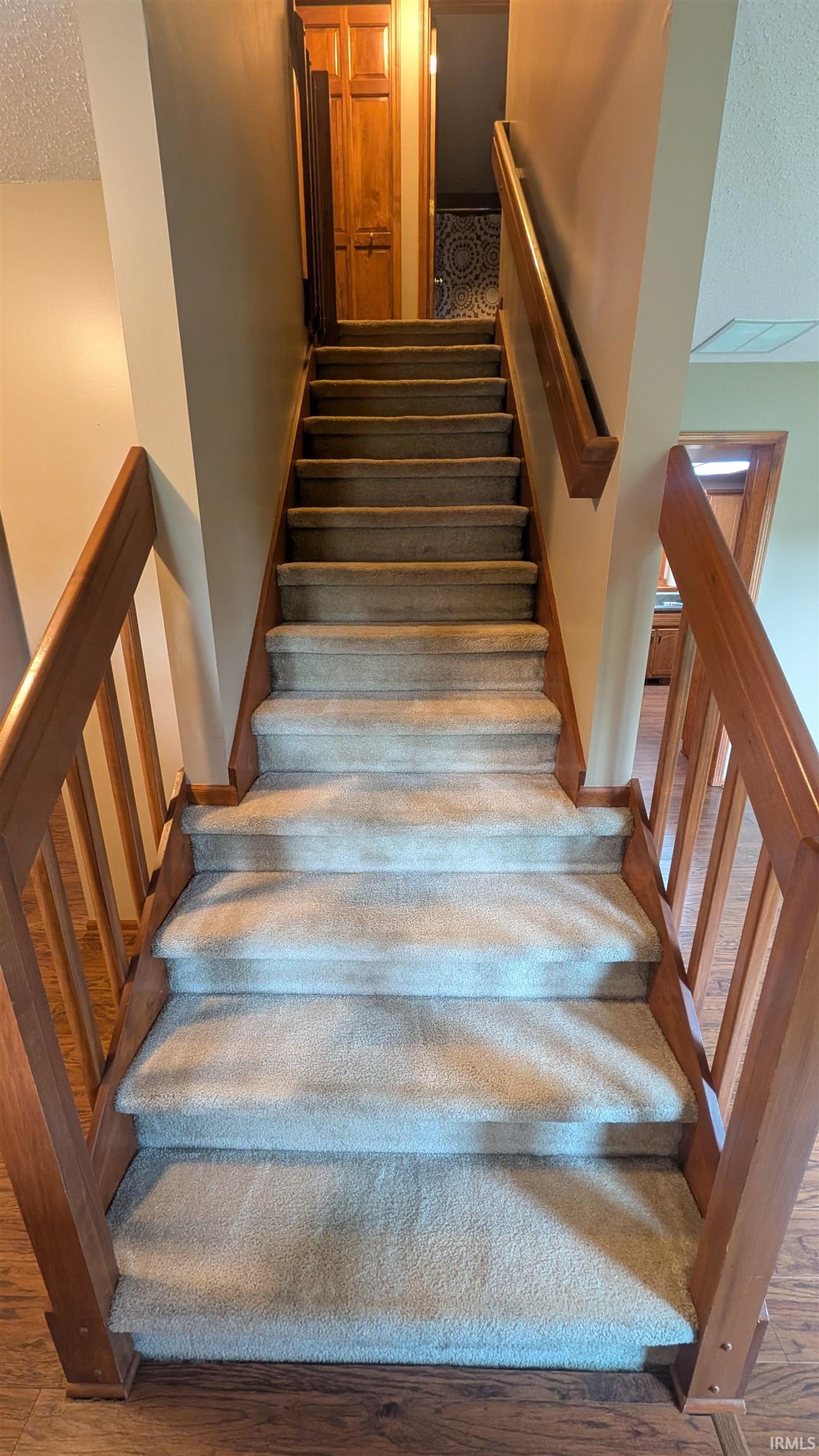 Carpeted staircase with wood-finish balusters and handrails