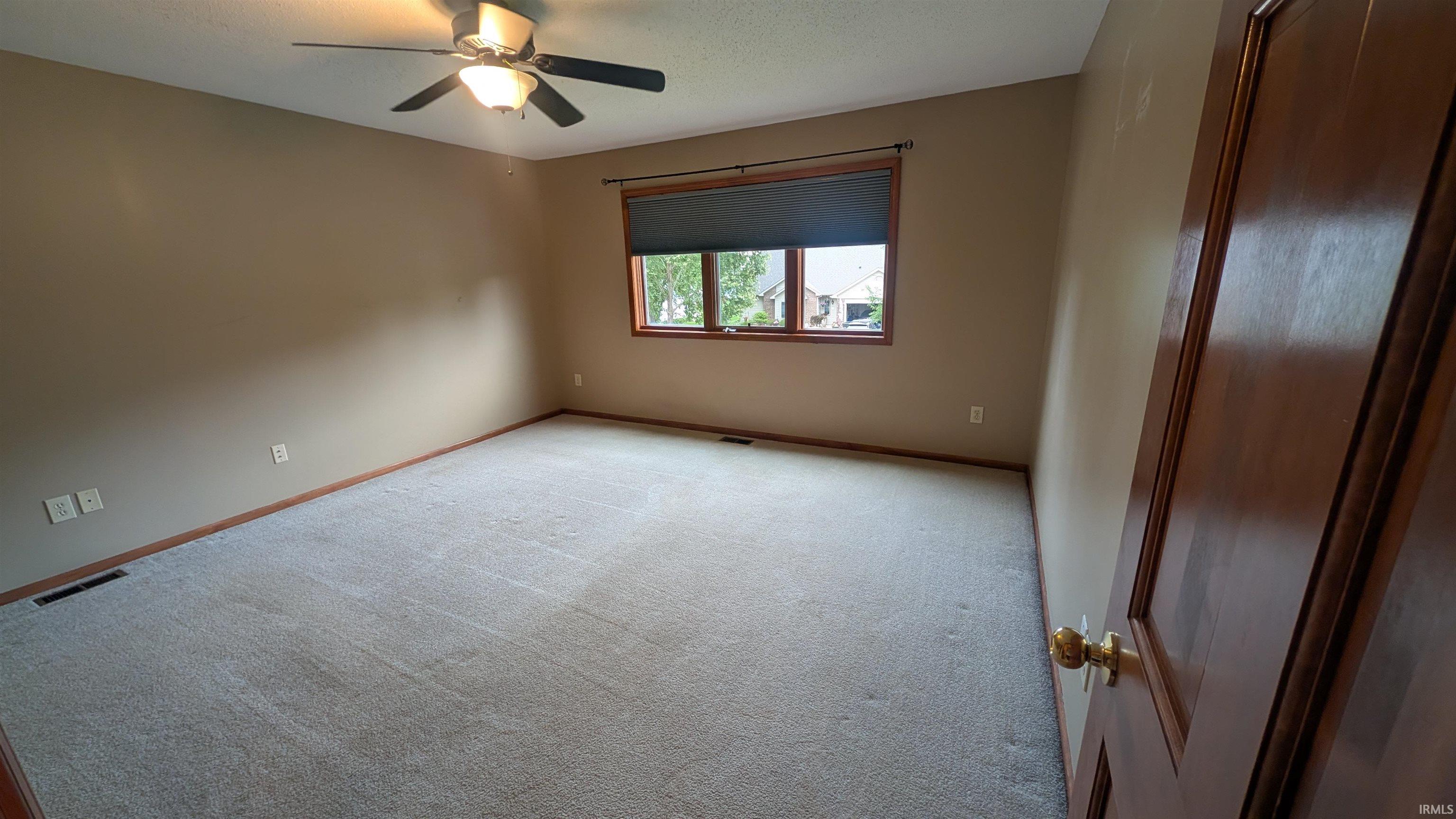 Spacious room featuring neutral carpeting and tan wall paint