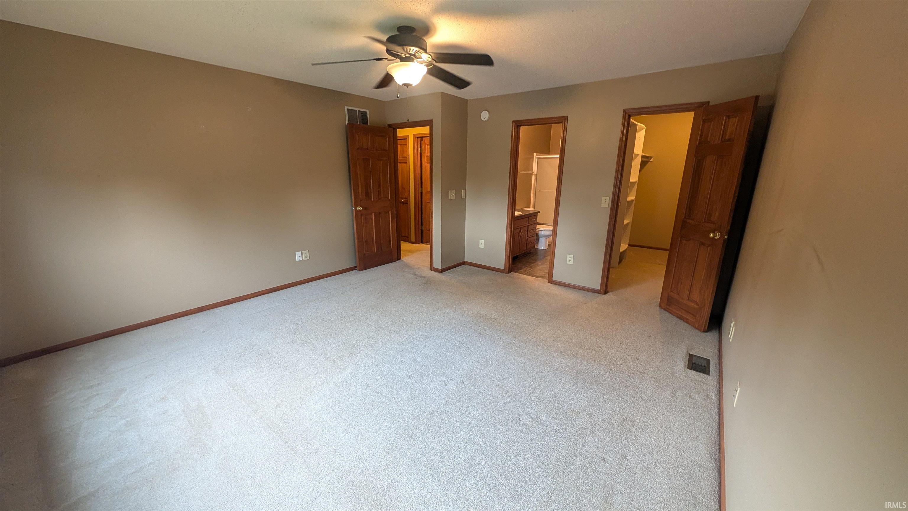Carpeted interior room featuring a ceiling fan with integrated lighting, wood-finish doors, and baseboard trim