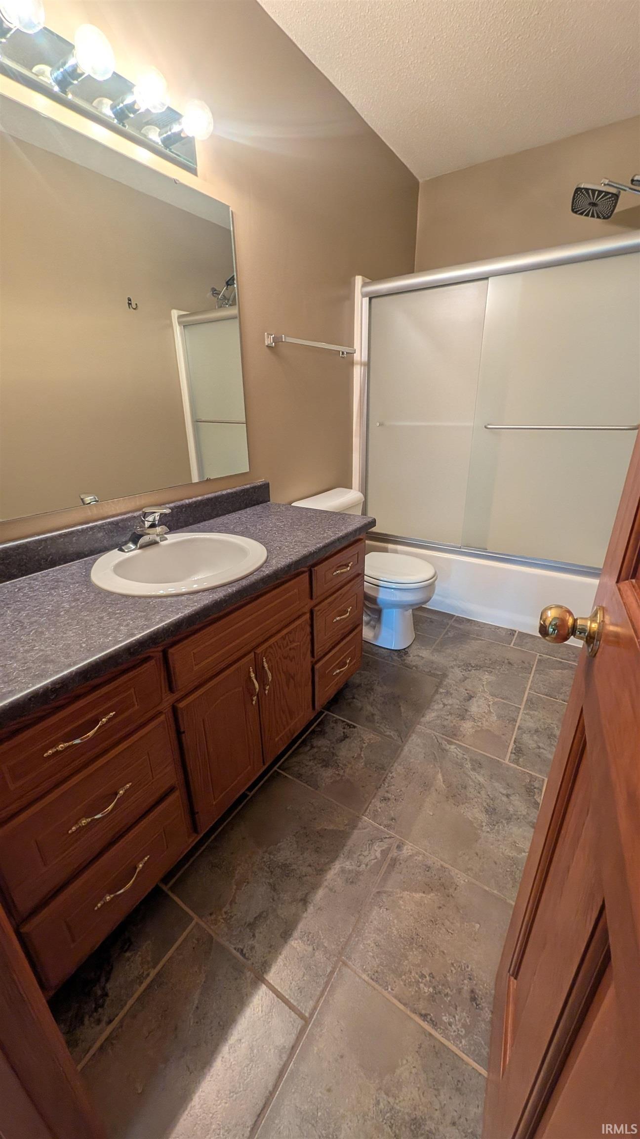 Bathroom featuring a single-sink vanity with wood-finish cabinetry, a white basin, and a dark countertop