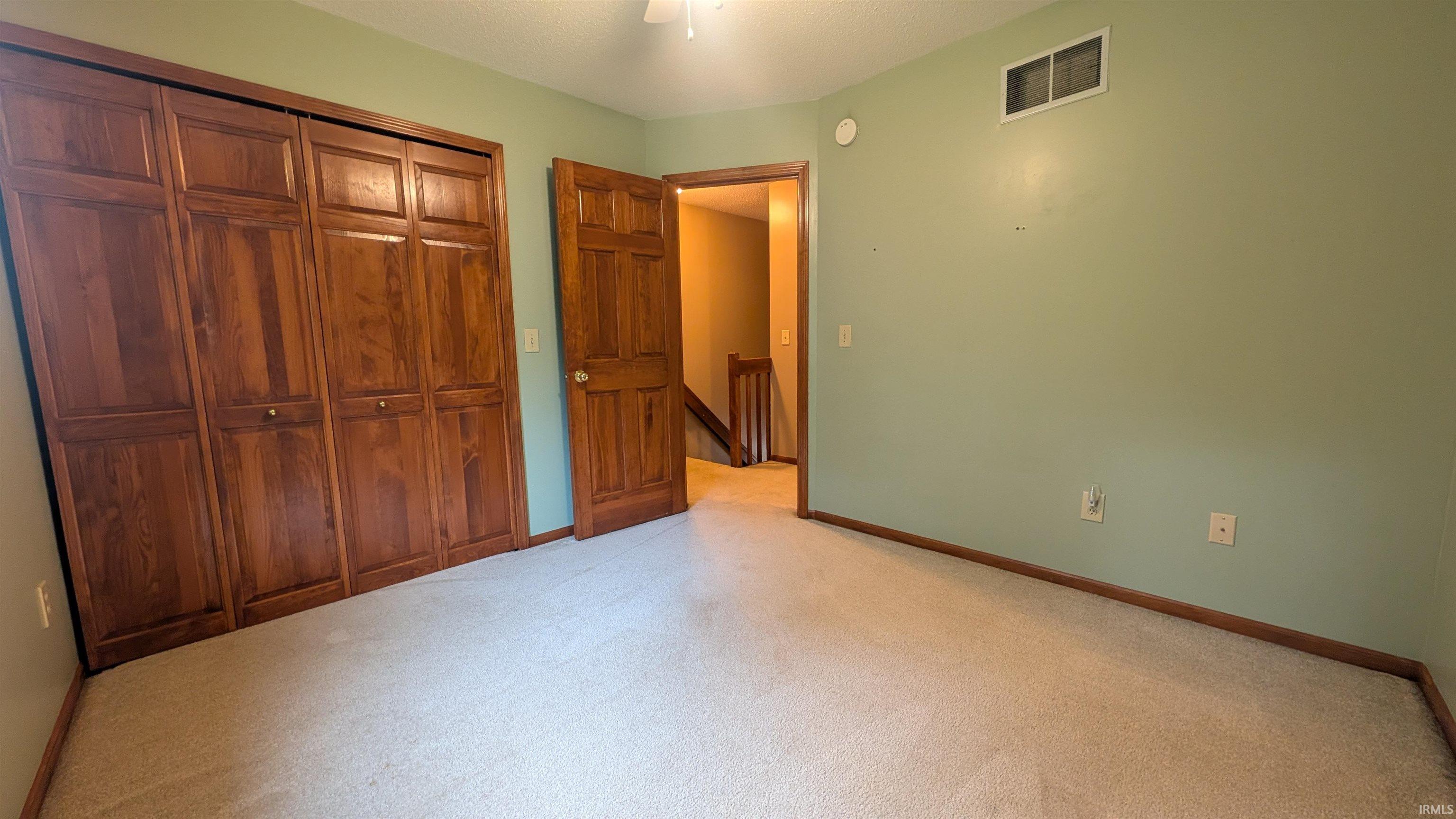 Bedroom featuring light green walls, beige carpeting, and dark wood-finish trim