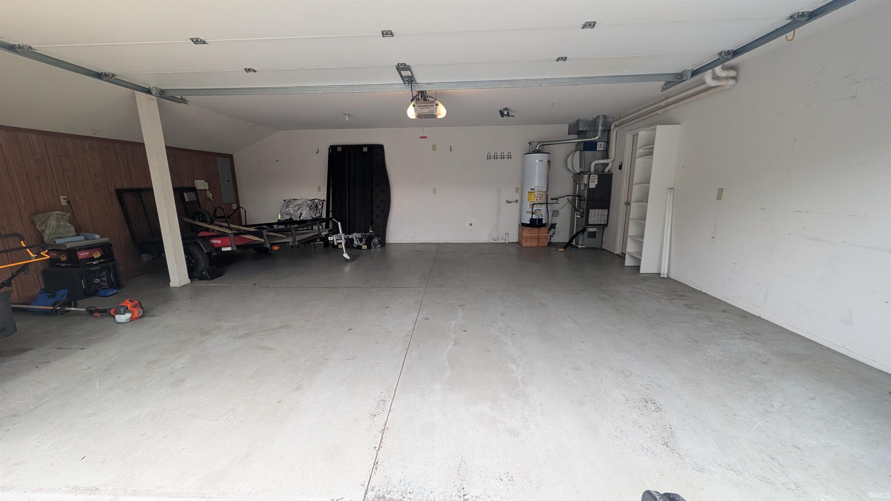 Spacious garage featuring a concrete floor, overhead lighting, and white painted walls