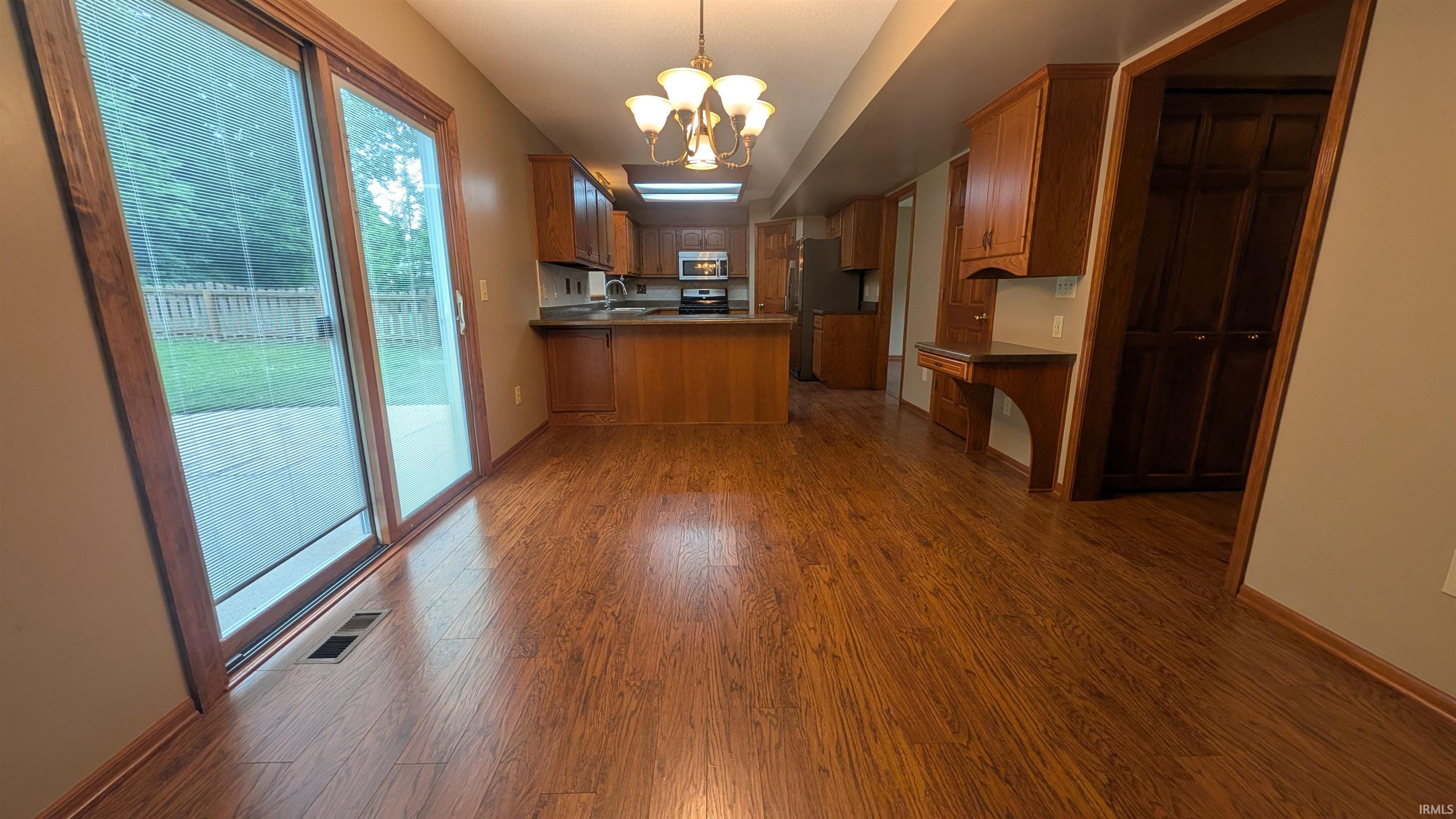 Expansive wood-finish flooring throughout, complemented by a sliding glass door leading to a patio