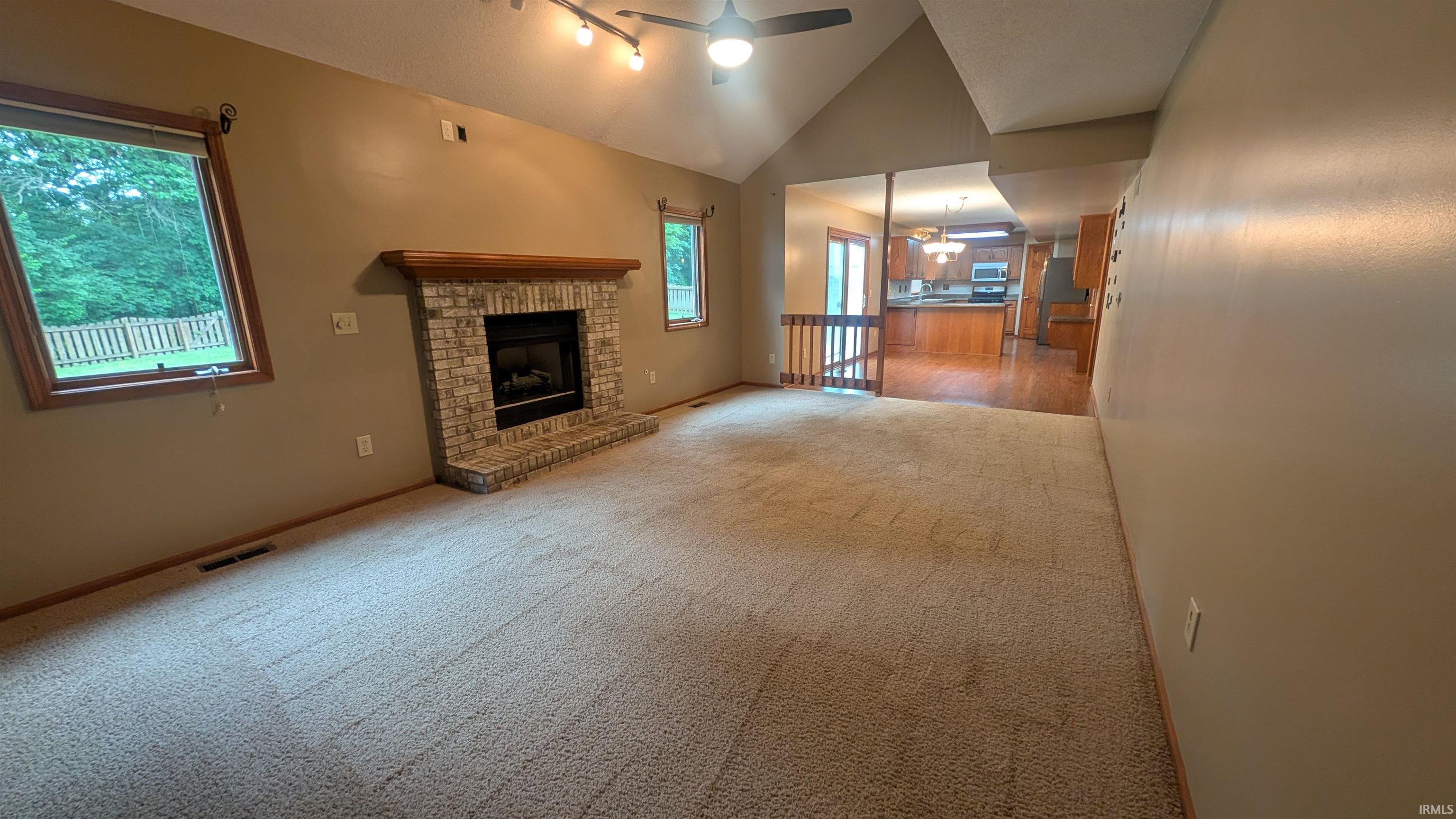 Spacious living area featuring a vaulted ceiling and a ceiling fan
