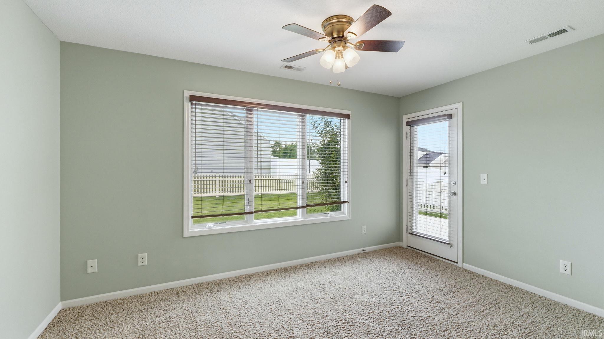 Carpeted room with a ceiling fan, a window with blinds, and a glass-paneled door