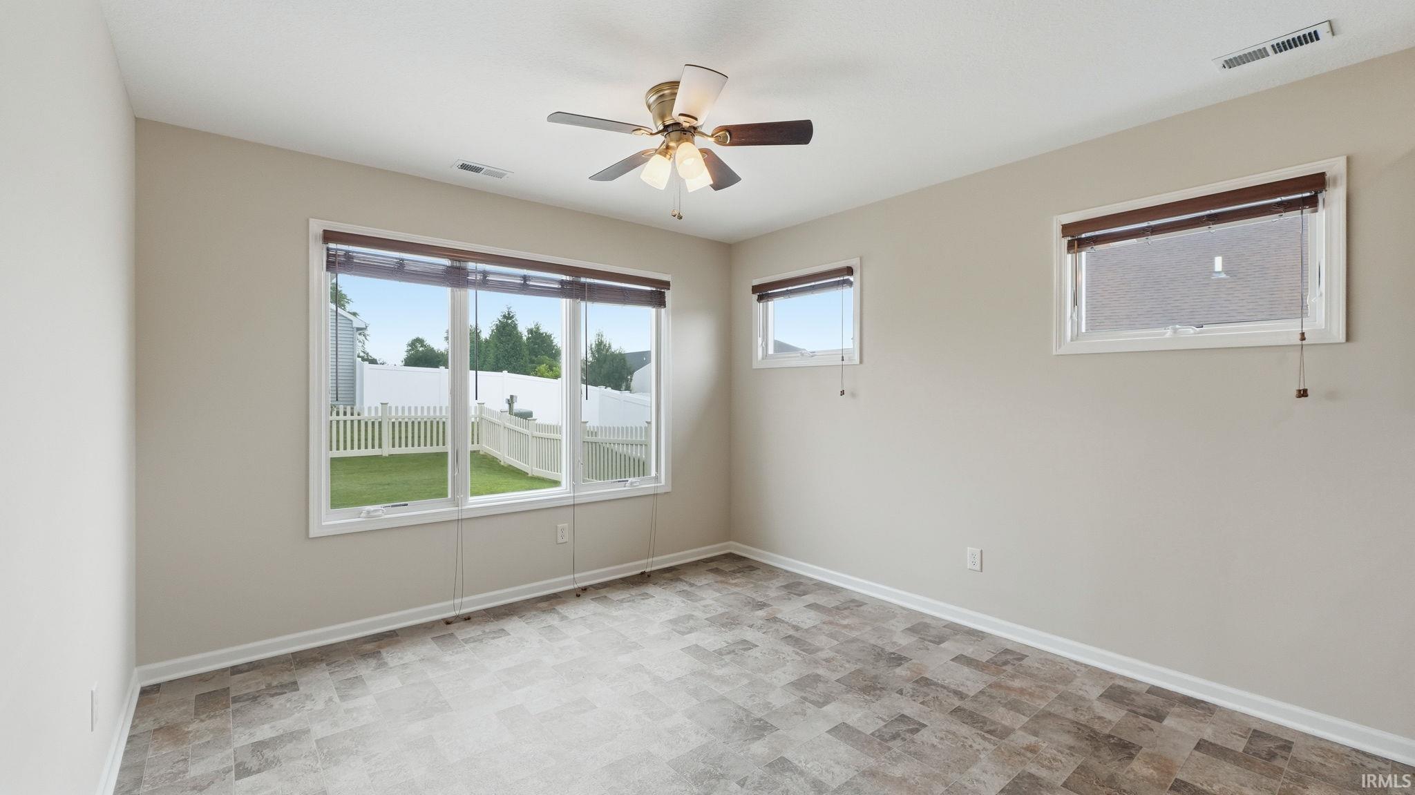 Room featuring multi-pane windows, a ceiling fan, and patterned tile flooring