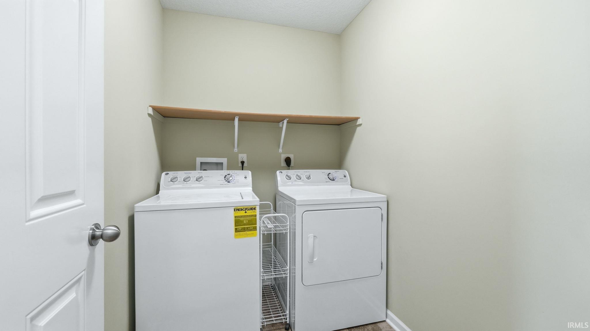 Dedicated laundry area featuring a light wood-finish shelf, neutral wall tones, and wood-finish flooring