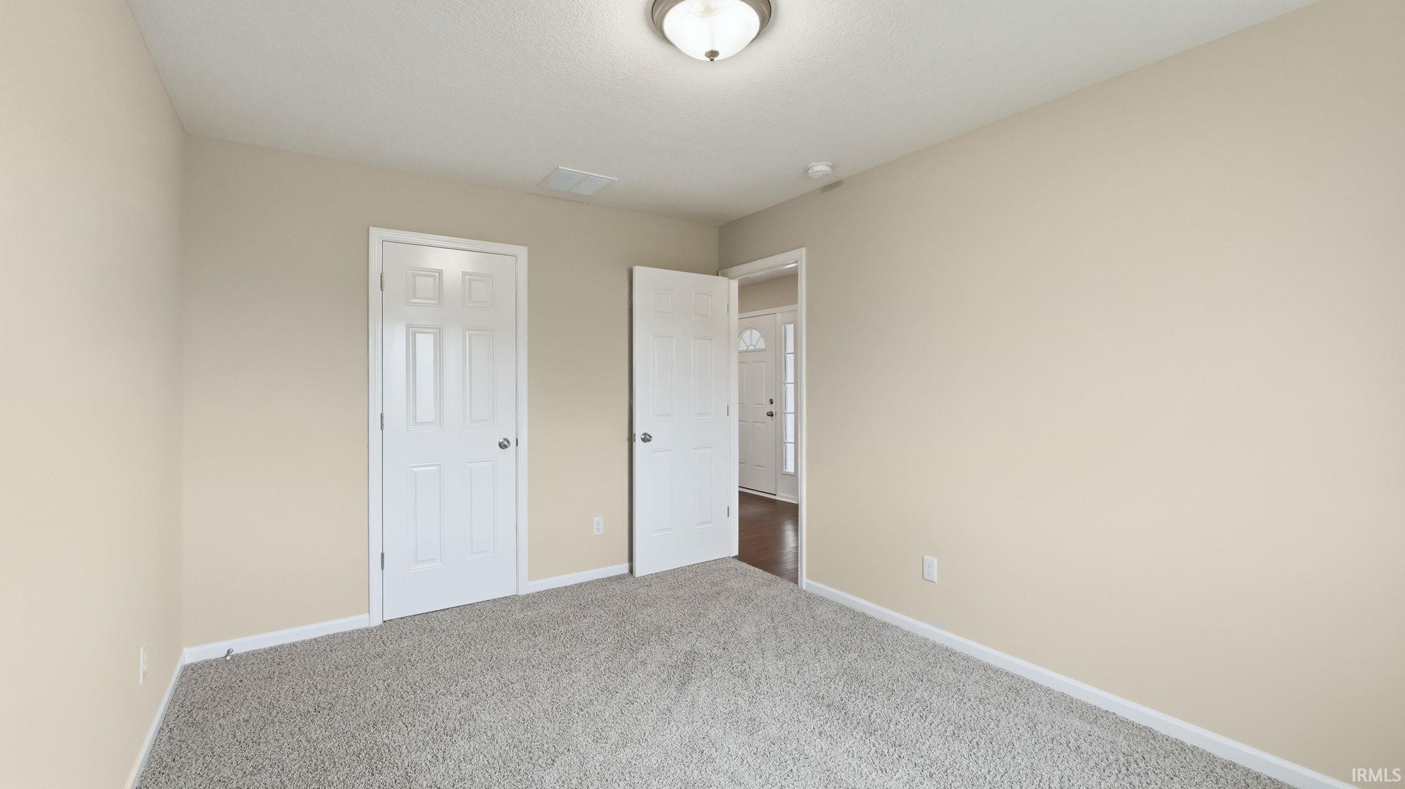 Neutral-toned room featuring light beige walls and plush grey carpet flooring