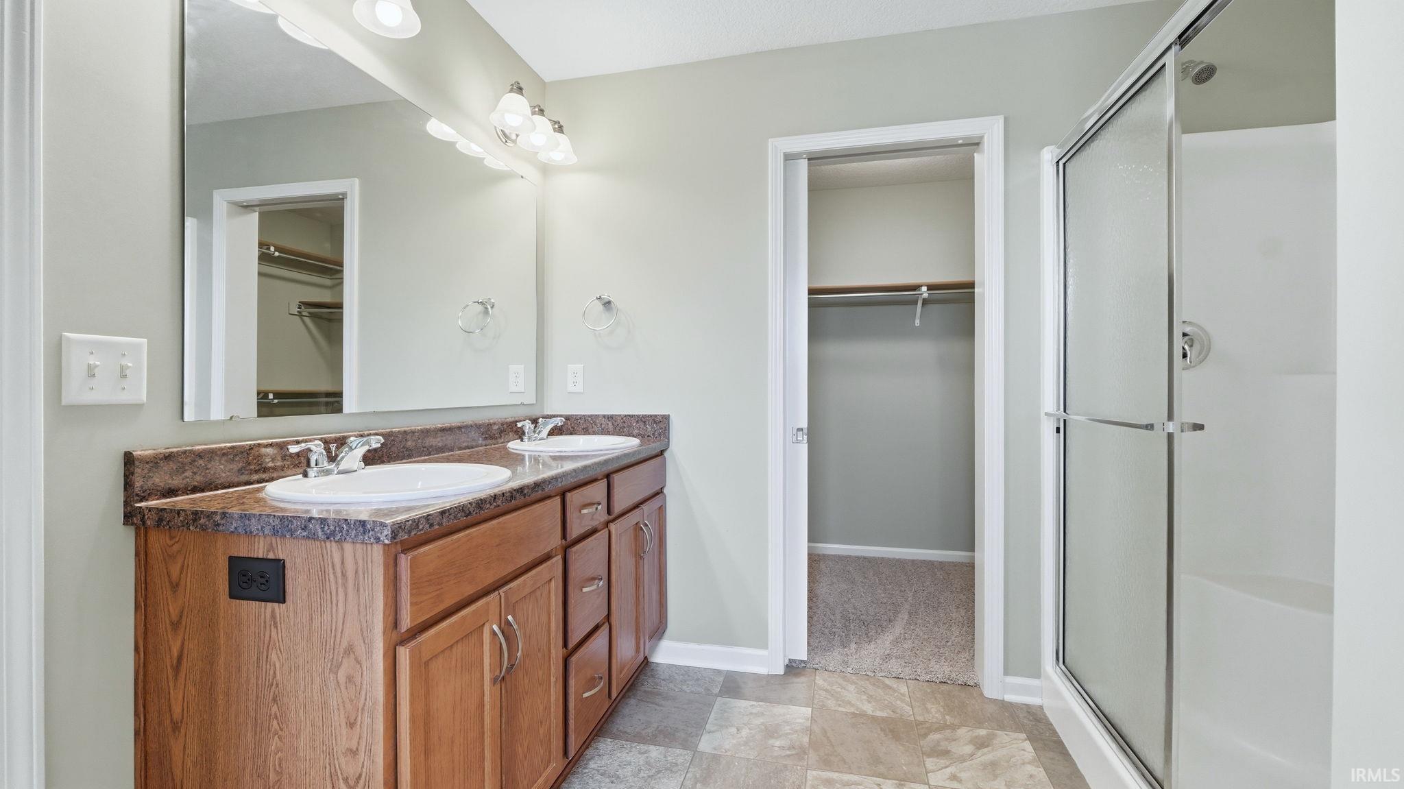 Bathroom featuring a double vanity with wood-finish cabinetry and a single-piece countertop