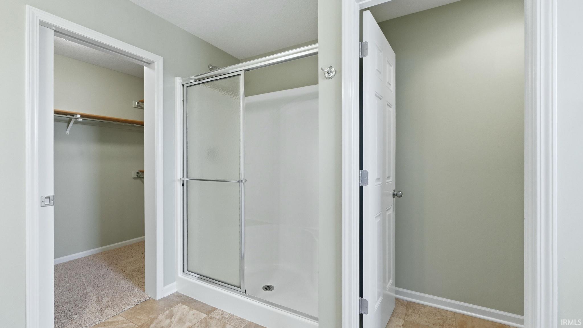 Shower enclosure with sliding glass doors, chrome hardware, and a white base