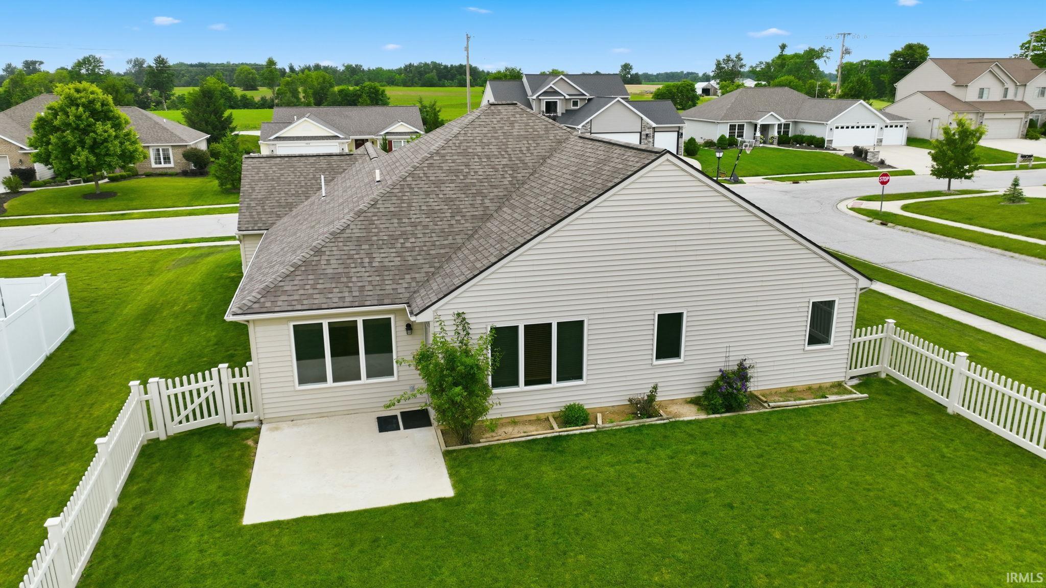 Backyard featuring a concrete patio, white picket fencing, and surrounding green lawn