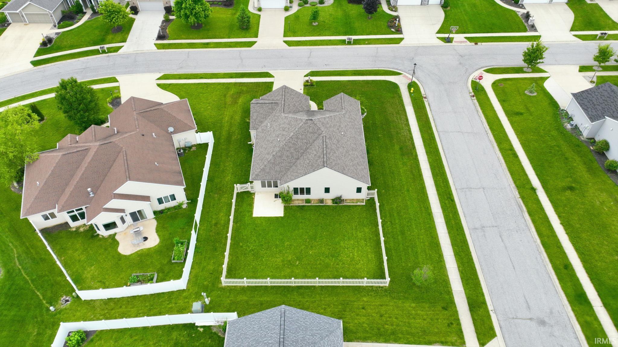 Rear elevation of a single-story residence featuring a private fenced yard with a patio area and raised garden beds