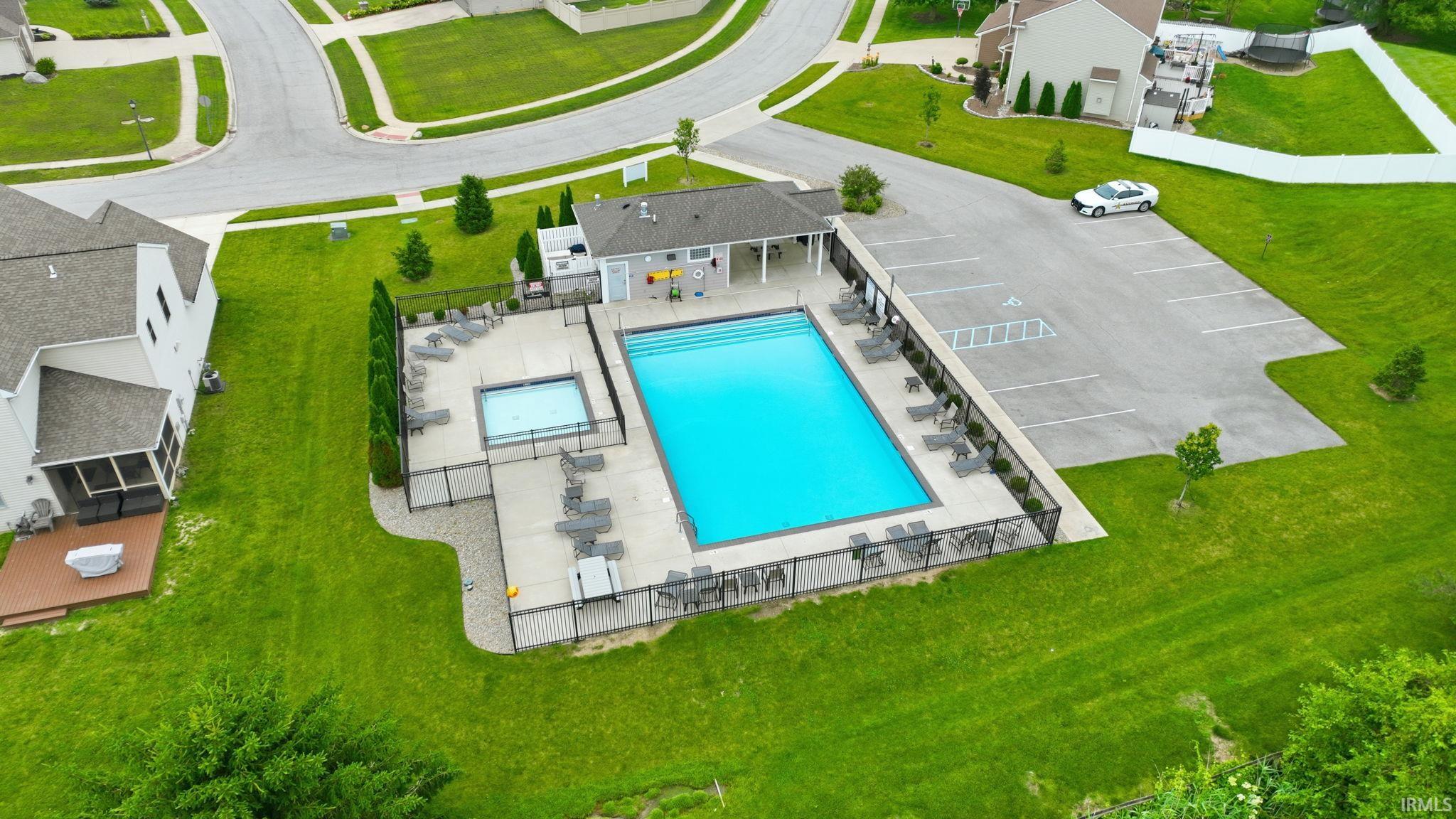 Community swimming pool with an integrated spa, expansive concrete pool deck, covered lounge area, and dedicated parking