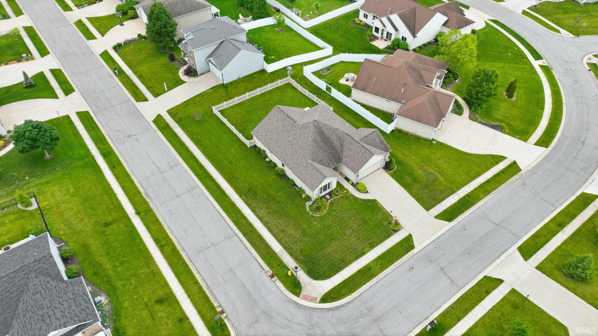 Spacious corner lot residence featuring a two-car garage, a paved driveway, and a white picket fence