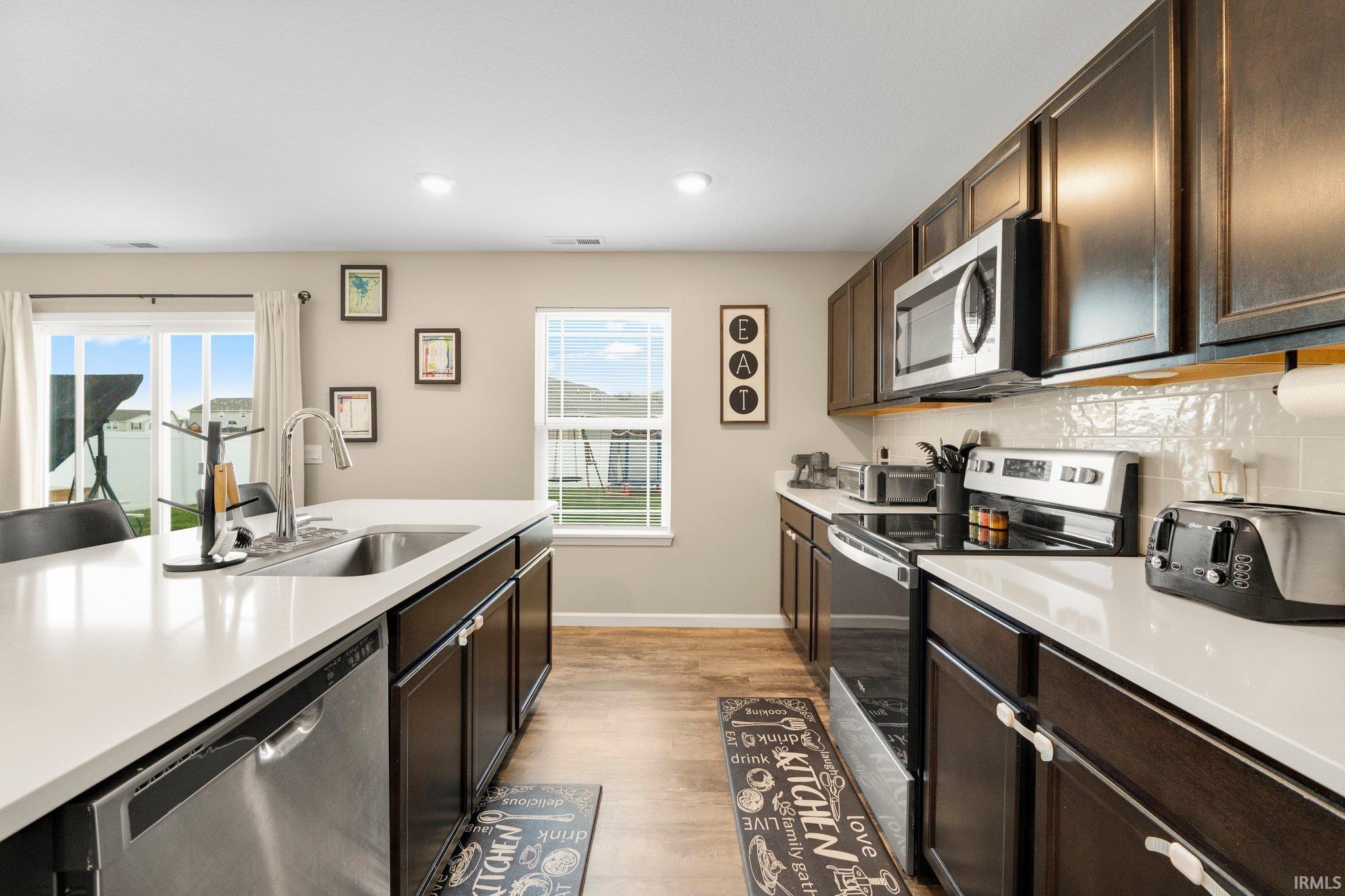 Modern kitchen featuring dark wood cabinetry, light-colored countertops, and stainless-steel appliances