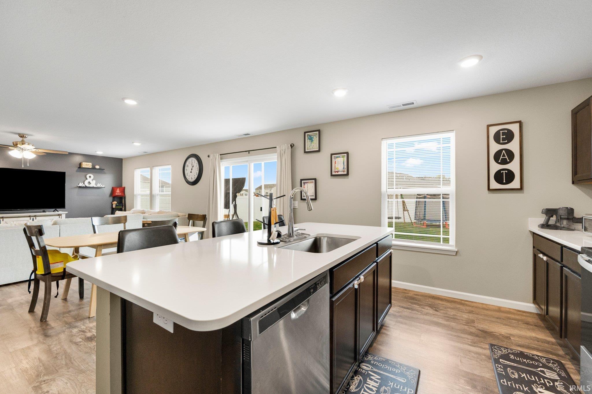 Open-concept kitchen featuring an island with an undermount sink, stainless steel dishwasher, and ample counter space
