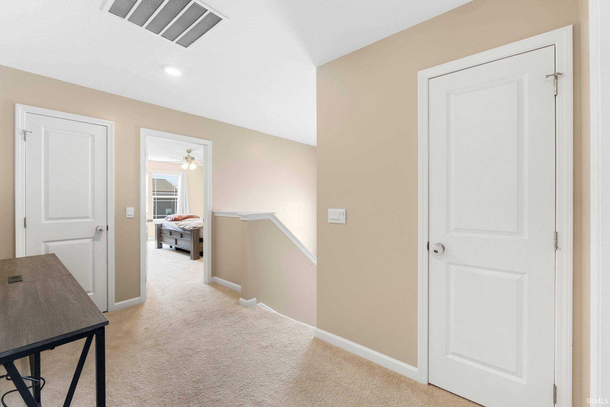 Upper-level hallway featuring neutral-toned carpet flooring and painted walls